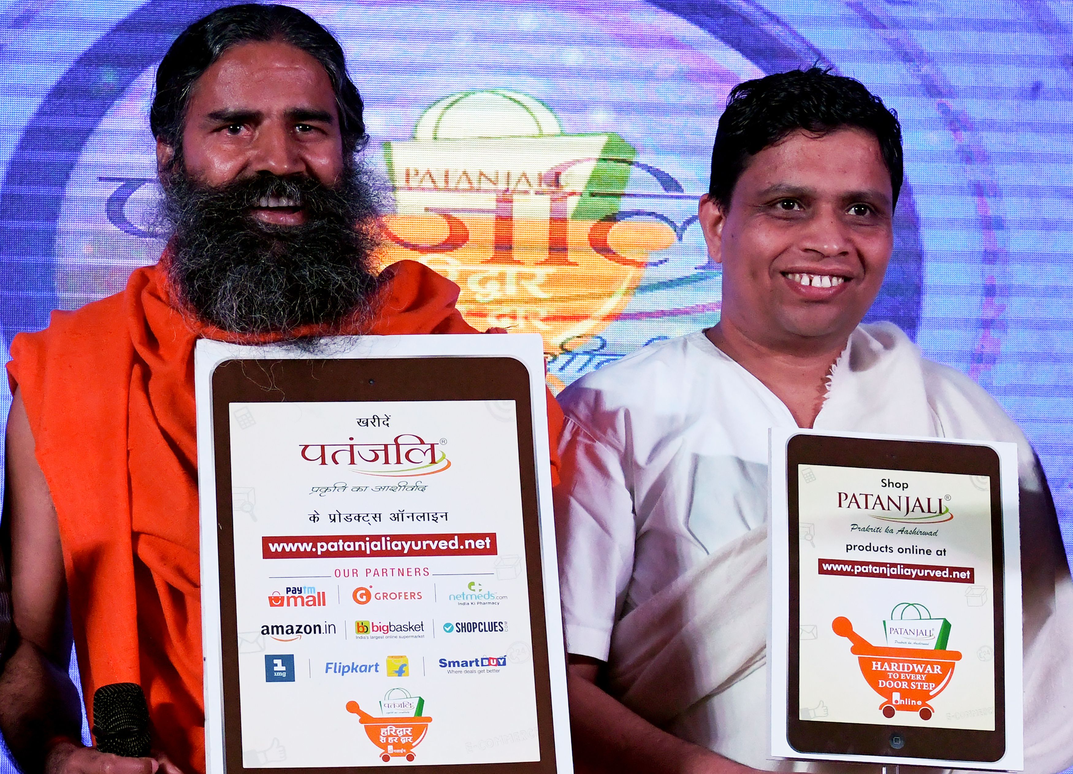 Indian yoga guru Baba Ramdev (L) and Patanjali Ayurveda Managing Director, Acharya Balkrishna, pose for a photo during a press conference in 2018