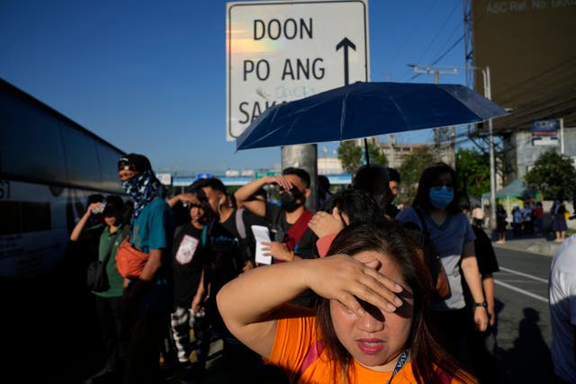 <p>Commuters use their hands to block the rays of the sun as they wait for a ride along a busy street in Quezon city, Philippines </p>