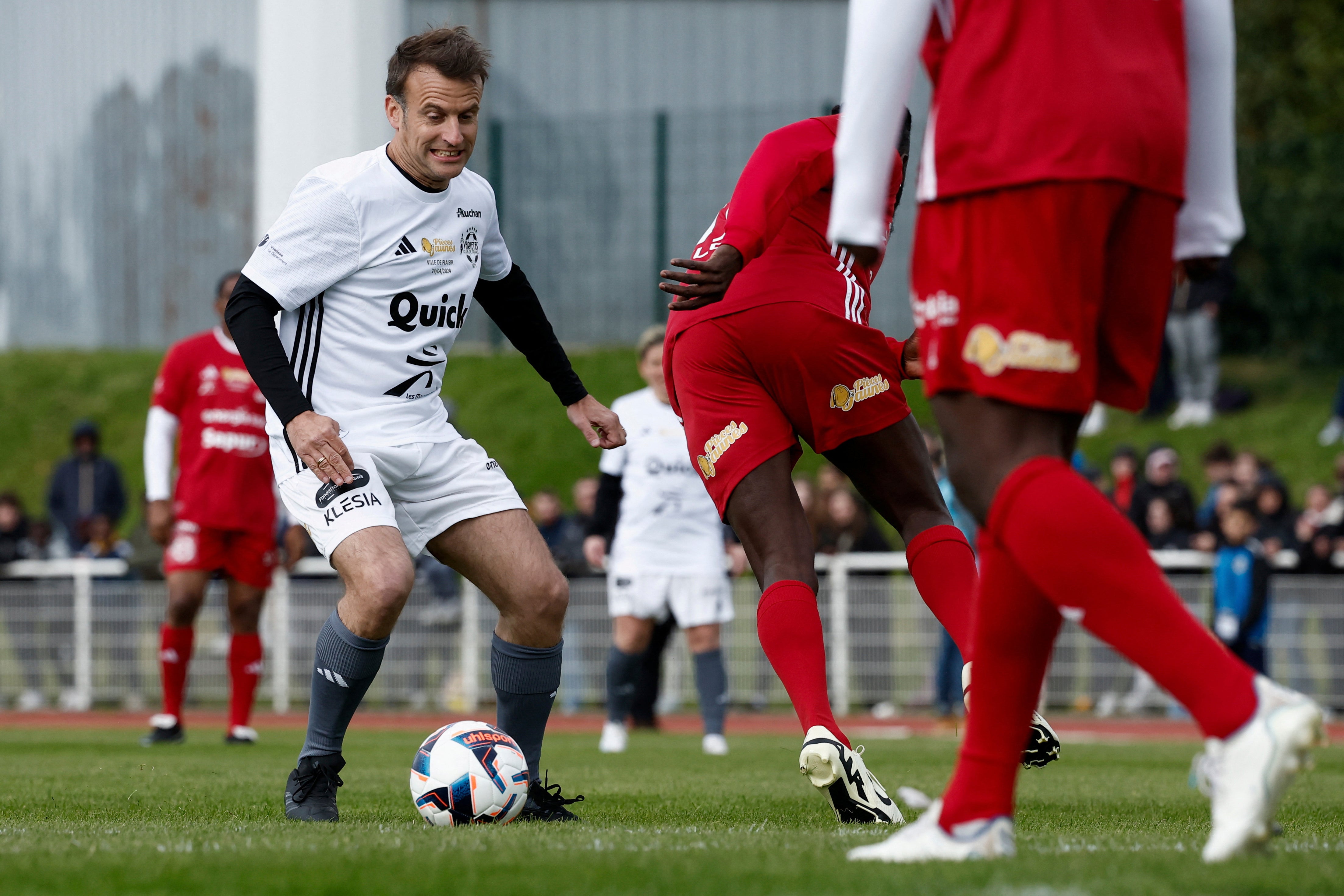 French President Emmanuel Macron controls the ball as he participates in the Varietes Club charity football match