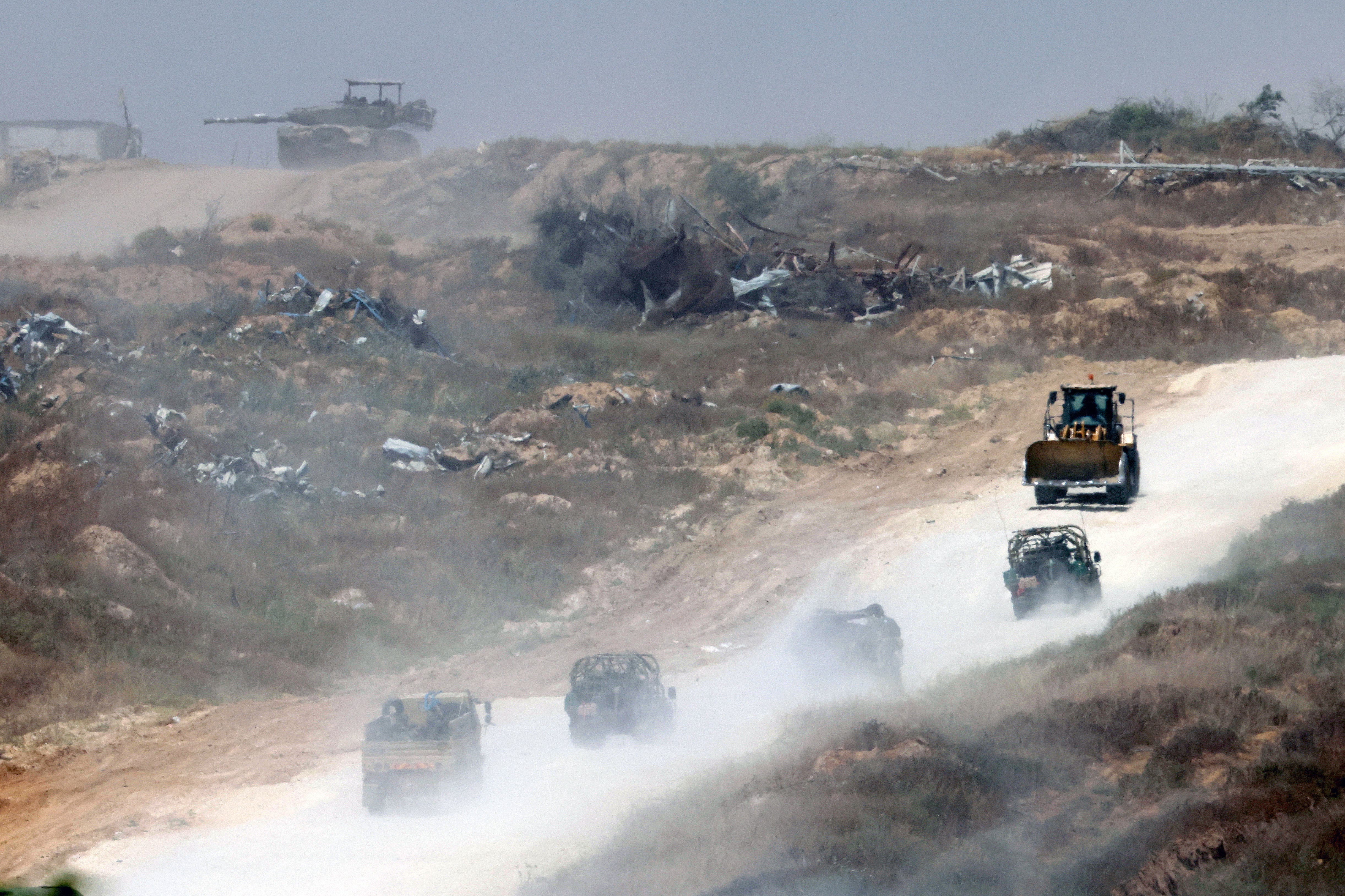 This picture taken from Israel’s southern border with the Gaza Strip shows Israeli military vehicles returning from the Palestinian territory on 24 April 2024, amid the ongoing conflict between Israel and the militant group Hamas