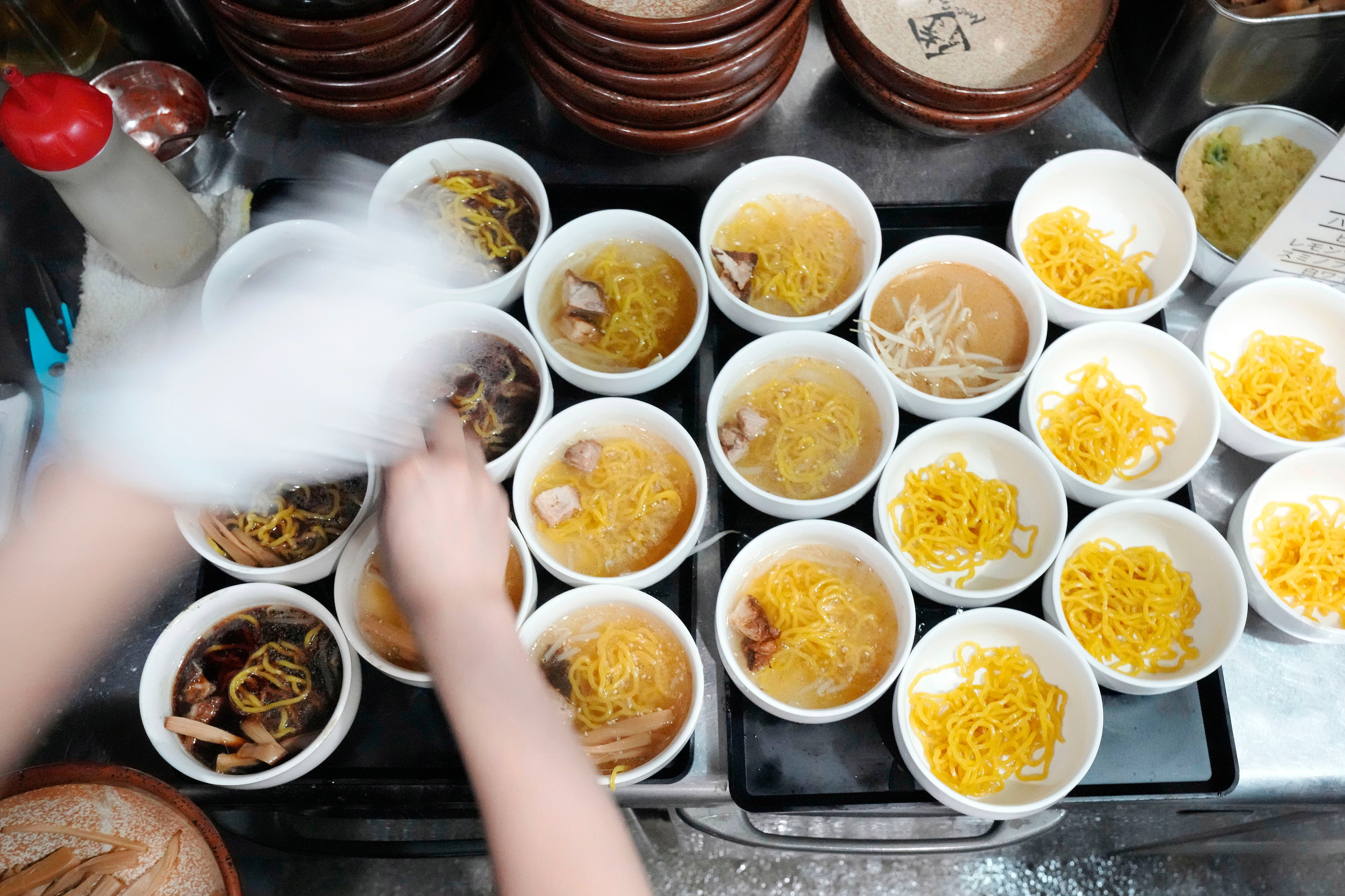 A staff member prepares small bowls of noodle for participants of Tokyo Ramen Tours at Shinbusakiya, a ramen shop