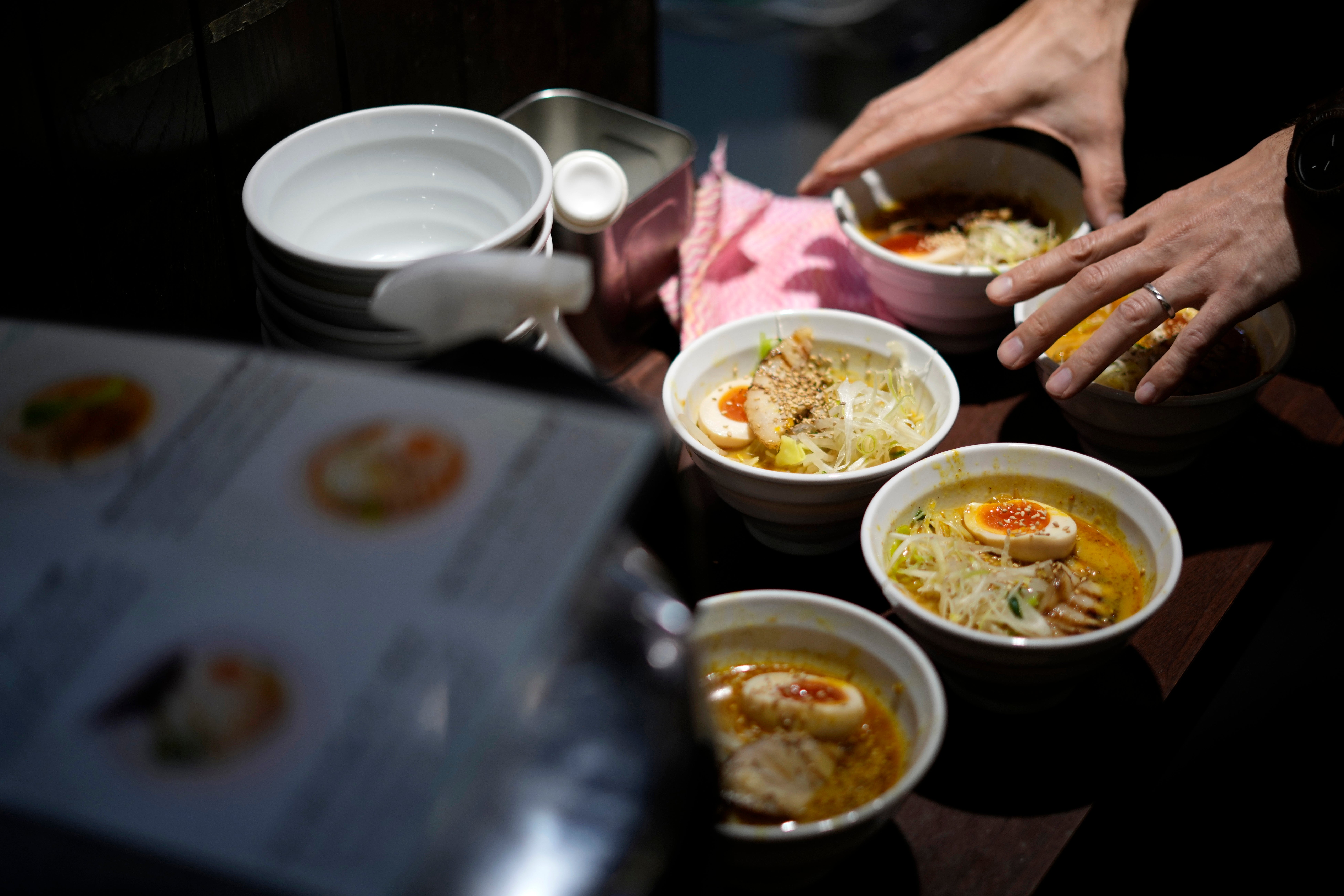 A staff member prepares to serve noodles for participants of Tokyo Ramen Tours at Syuuichi