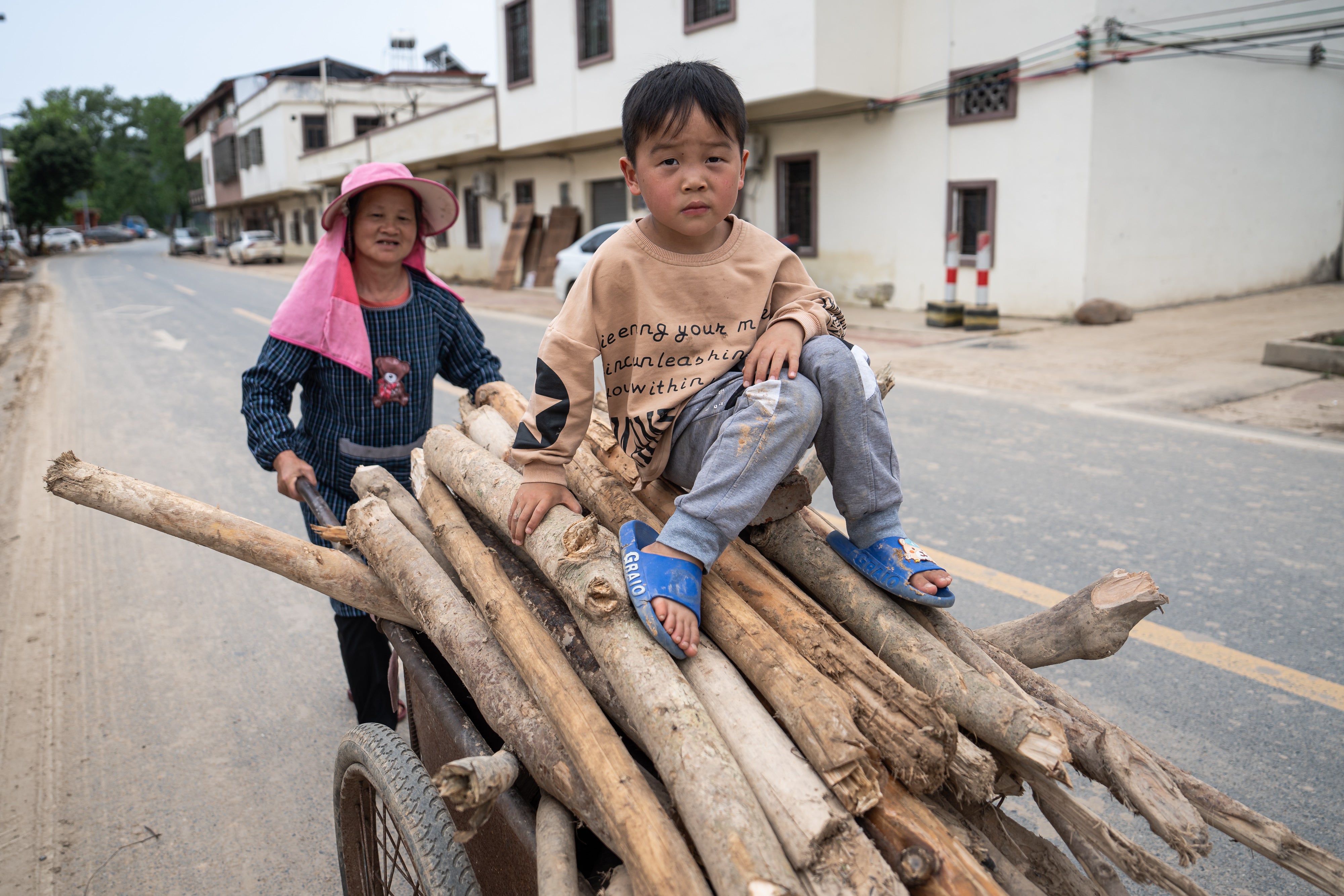 A child sits on a car loaded with firewood after the heavy rainfall on April 24, 2024 in Shaoguang, China.