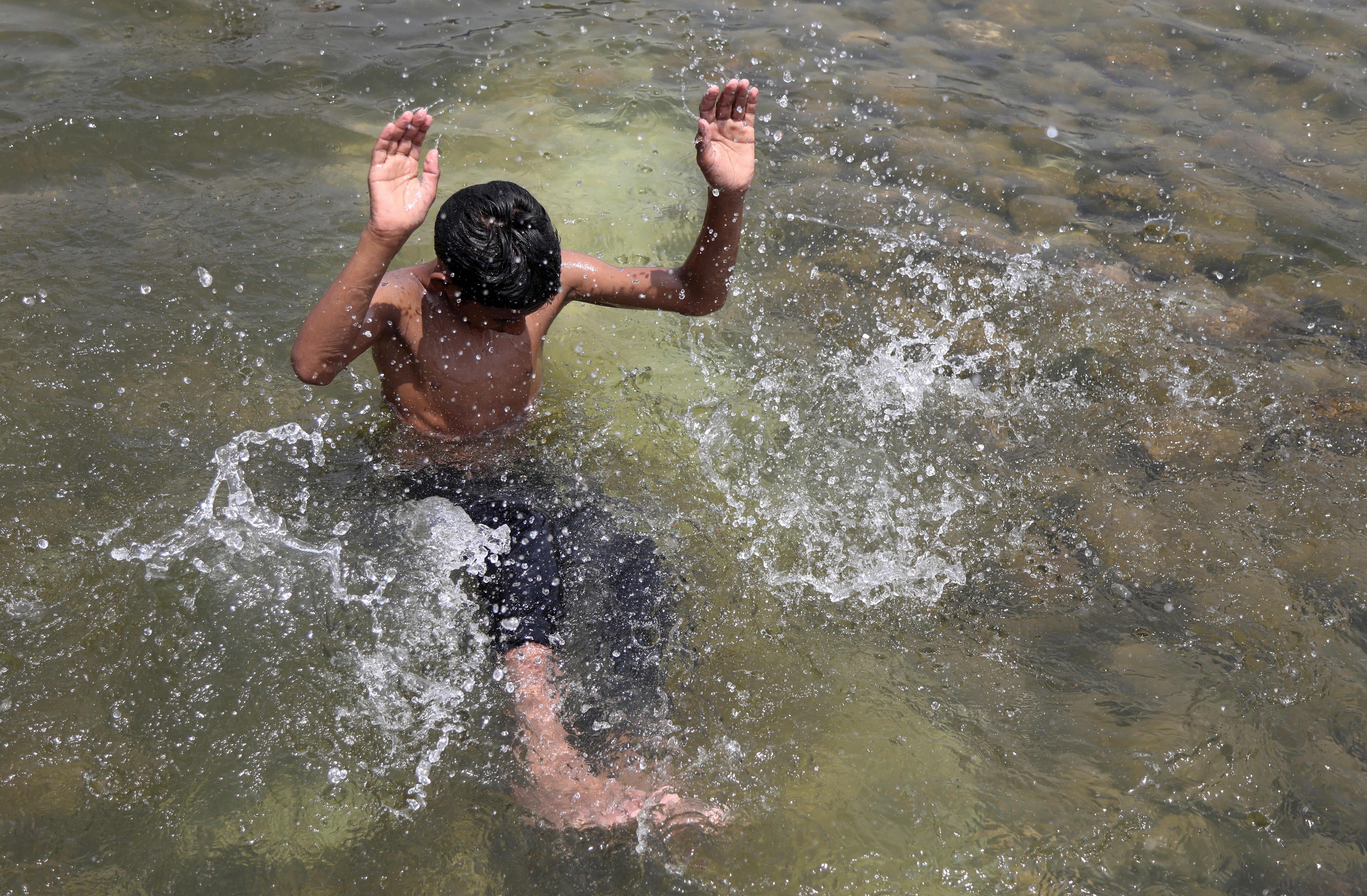 A boy cools off during the heatwave at the Suhrawardy Udyan water reserve in Dhaka