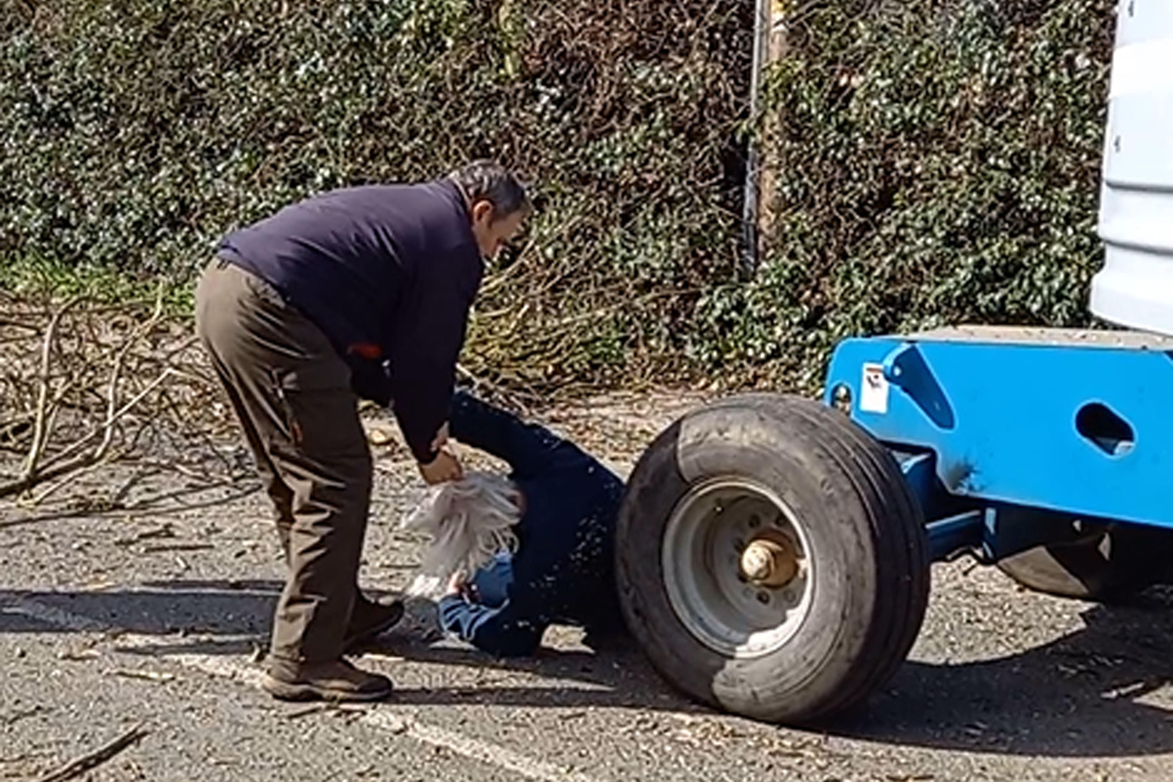 Andrew Mason in front of a tree-cutting cherry-picker as Chris Makin tries to drag him by his clothes and hair (Andrew Mason/PA)