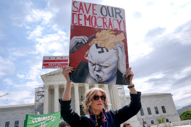 A demonstrator stands outside the Supreme Court as the justices prepare to hear arguments over whether Donald Trump is immune from prosecution in a case charging him with plotting to overturn the results of the 2020 presidential election, on Capitol Hill Thursday, April 25, 2024, in Washington.