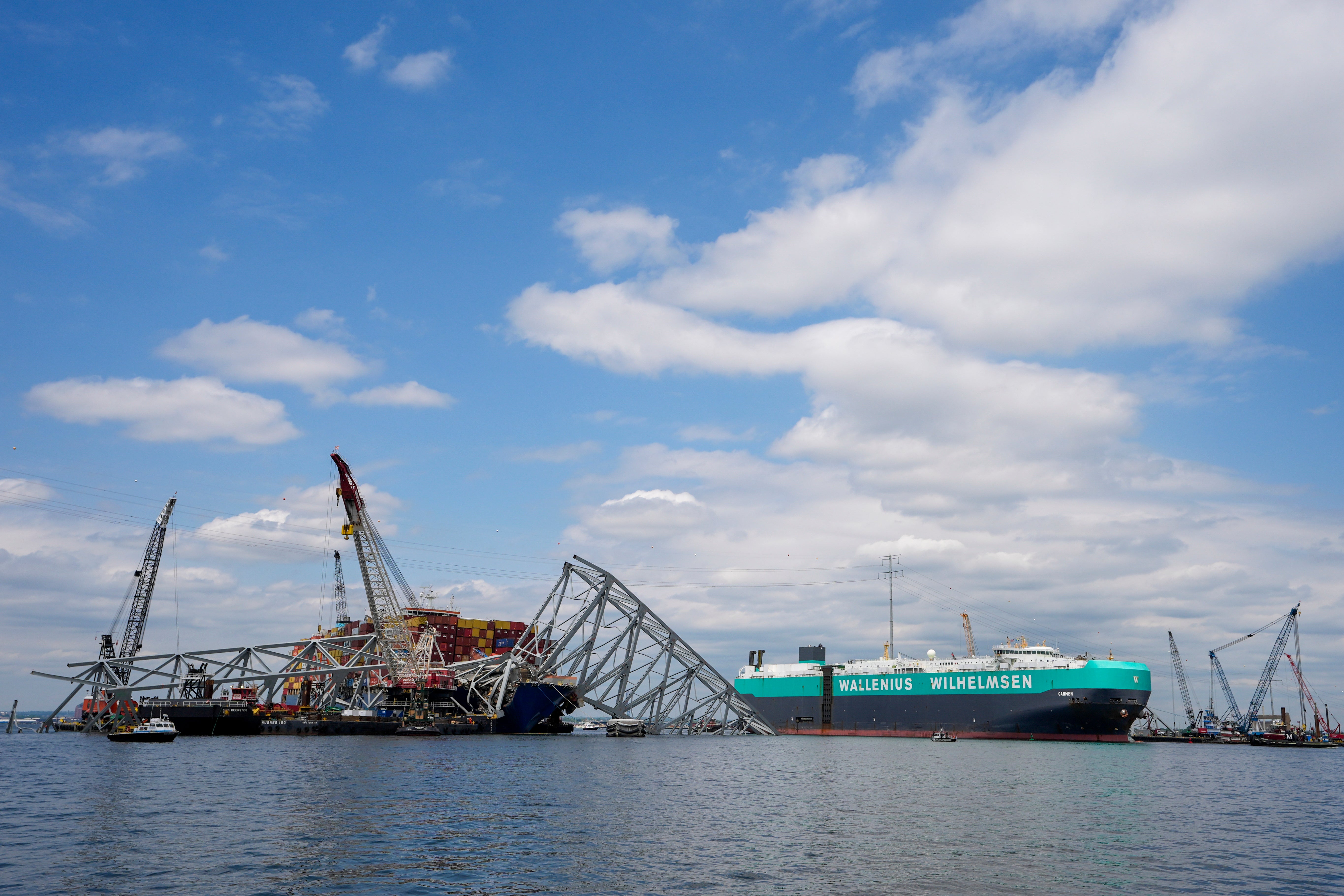 A vessel, center right, moves past the stranded container ship Dali, through a newly opened deep-water channel in Baltimore after being stuck in the harbor since the Francis Scott Key Bridge collapsed