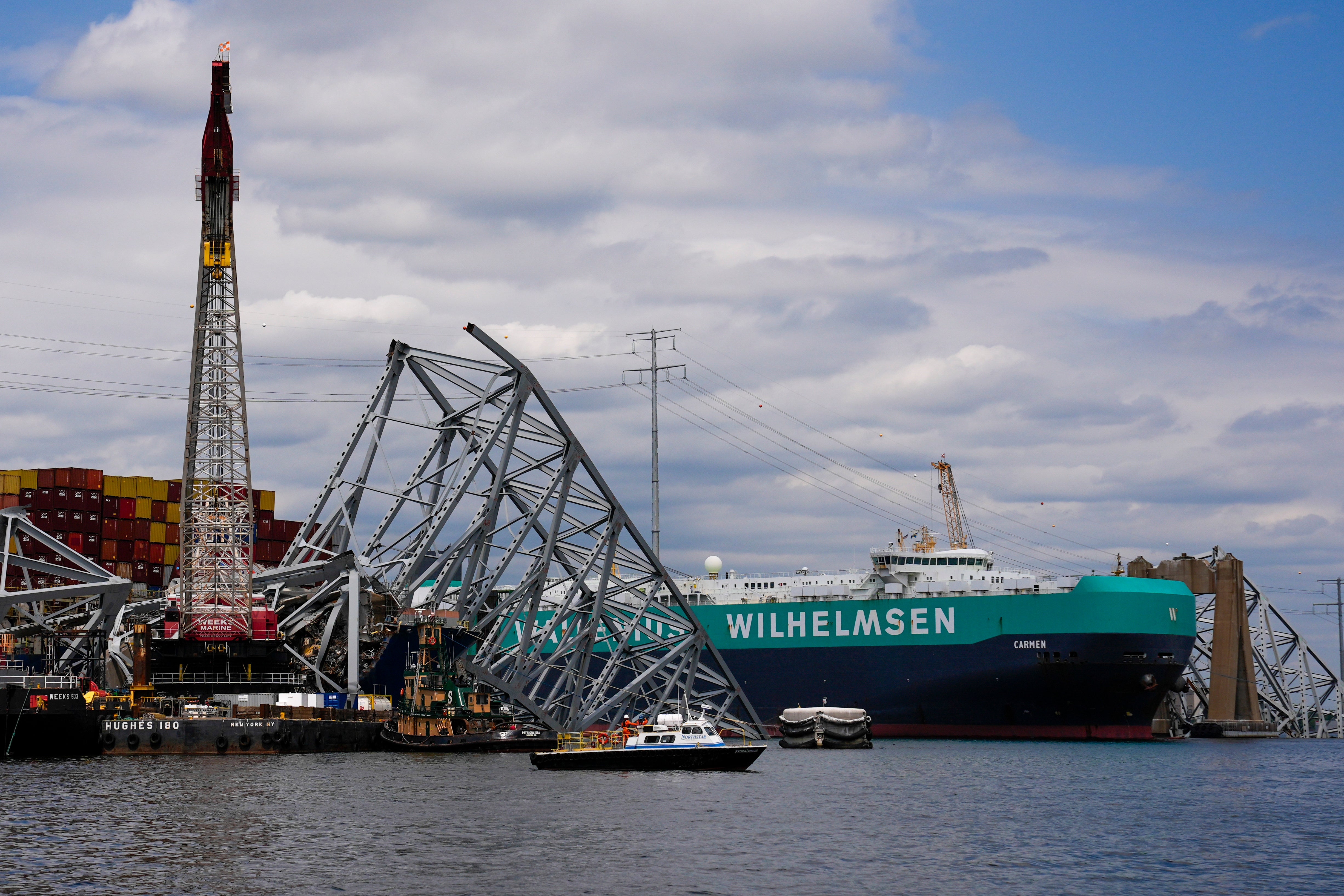 A vessel, center right, moves past the stranded container ship Dali