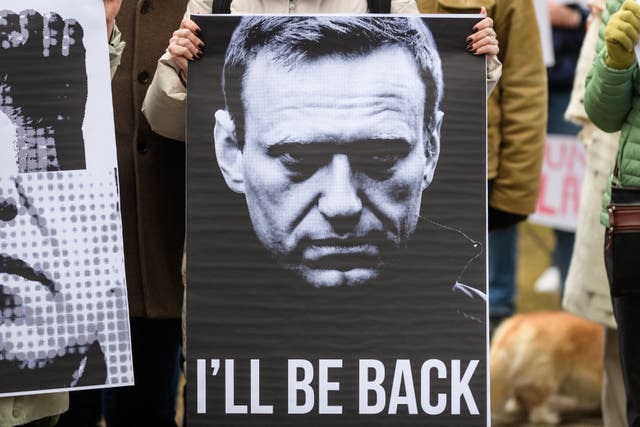 <p>A protester holds a sign showing late Kremlin opposition leader Alexei Navalny and reading ‘I’ll be back’, during a protest in Riga</p>