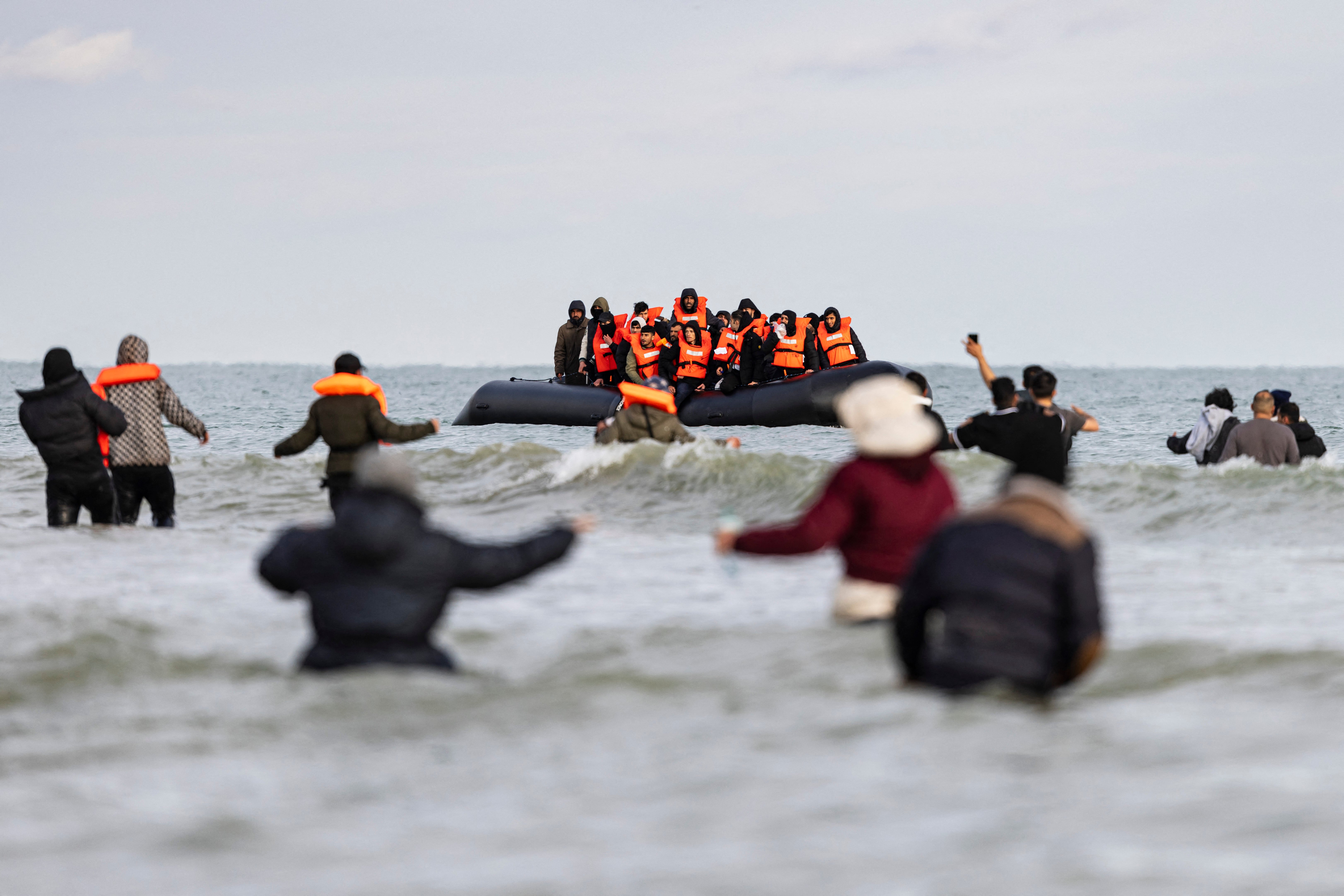 Migrants wave to a smuggler's boat in an attempt to cross the English Channel, on the beach of Gravelines, near Dunkirk