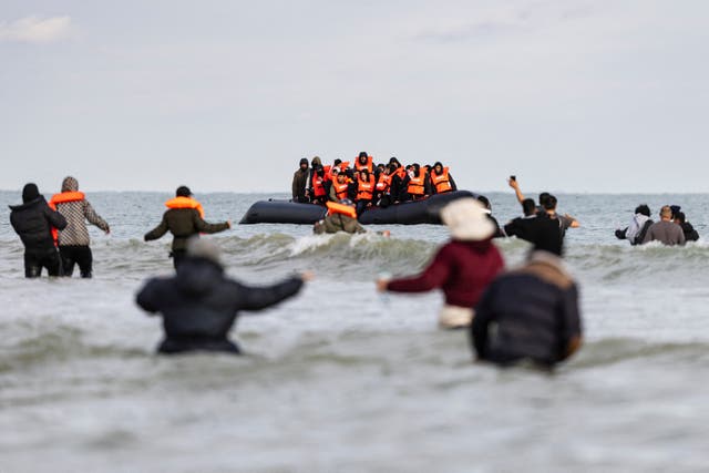 <p>Migrants wave to a smuggler's boat in an attempt to cross the English Channel, on the beach of Gravelines, near Dunkirk</p>