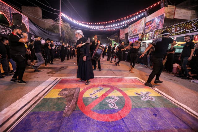 <p>Shia Muslim devotees self-flagellate over an unfurled banner on the ground depicting the Pride rainbow flag defaced with a boot and the Arabic slogan ‘no to homosexual society’ in the city of Nasiriyah in Iraq</p>