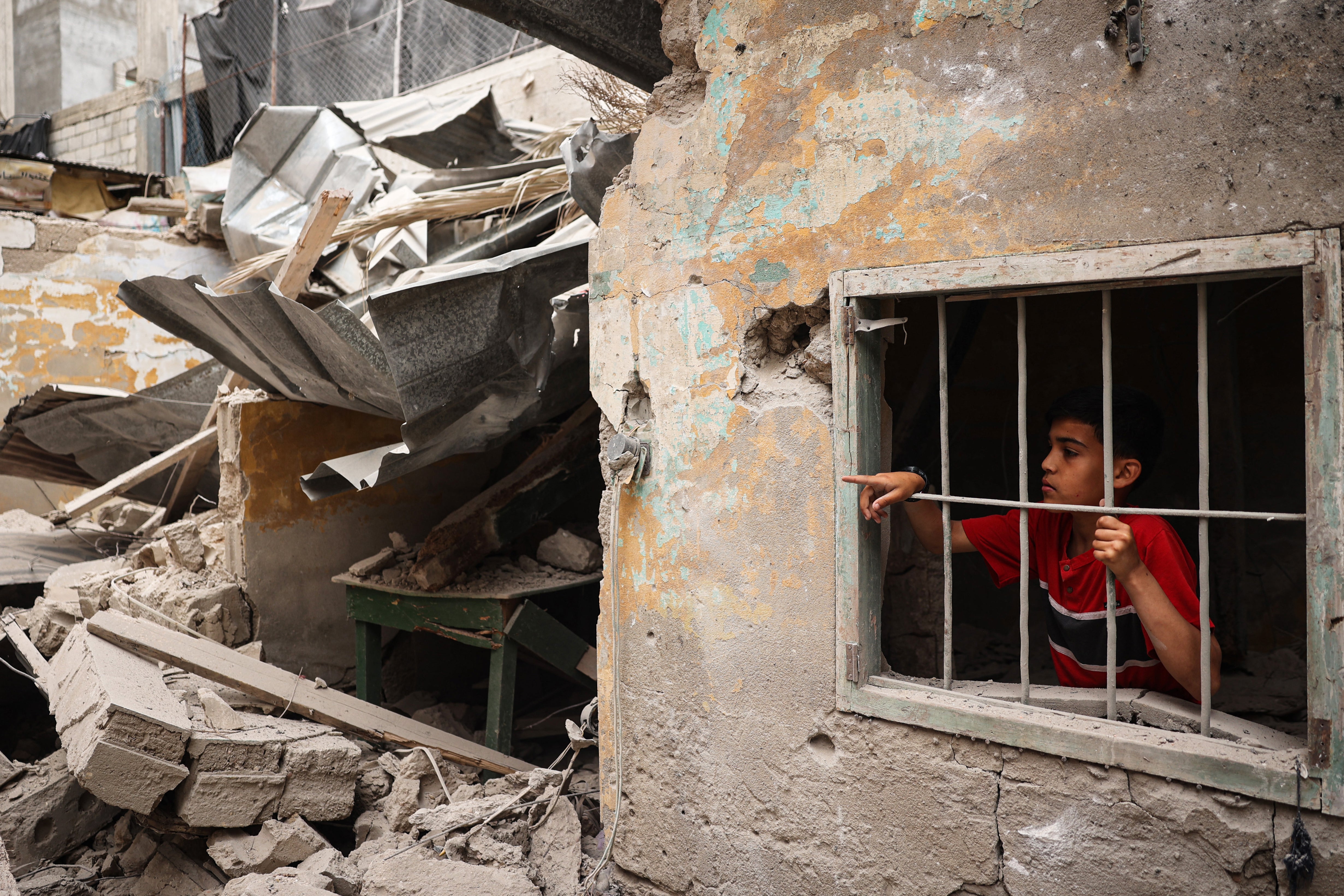 A Palestinian child looks out from the debris of a house destroyed by overnight Israeli bombardment in Rafah