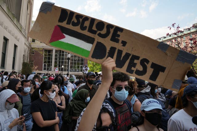 <p>A protester holds a sign during a march on Columbia University campus in support of a protest encampment supporting Palestinians, despite a 2pm deadline issued by university officials to disband or face suspension on 29 April 2024 </p>