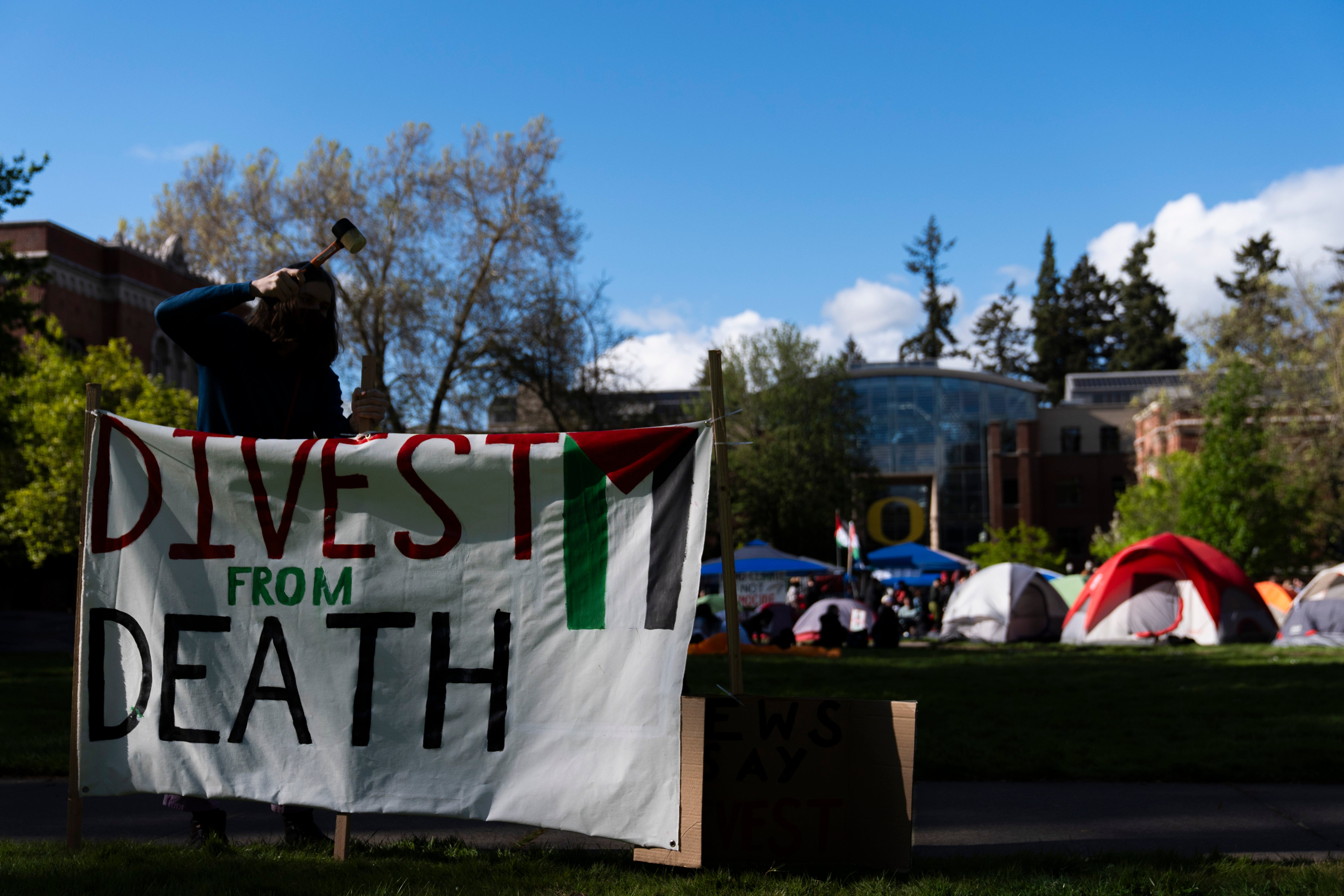 A student at the University of Oregon sets up a sign that reads "Divest from death" as students set up a tent encampment at the university to protest the Israel-Hamas war on Monday, April 29, 2024