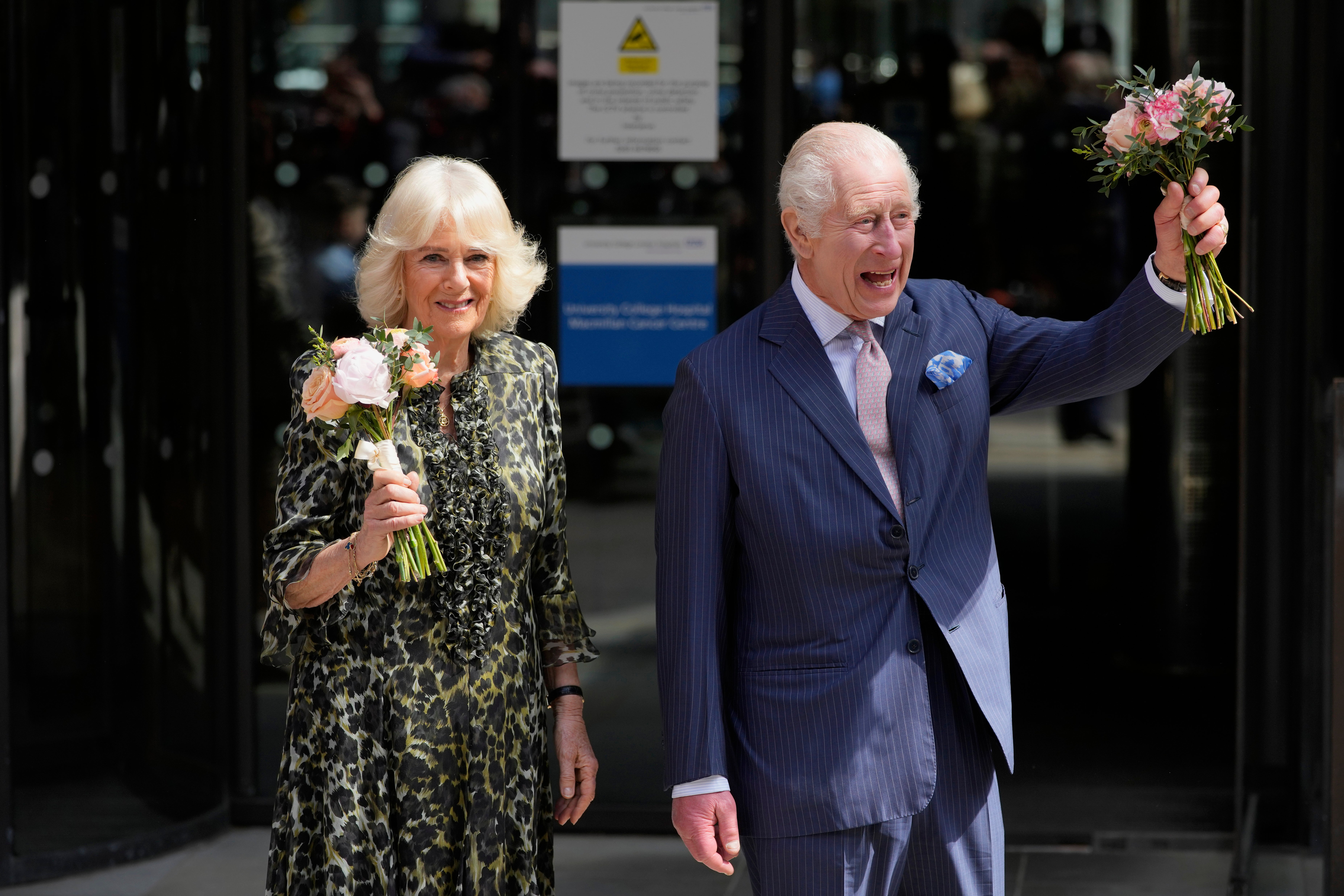 King Charles III and Queen Camilla hold flowers they were given as they leave after the visit on Tuesday