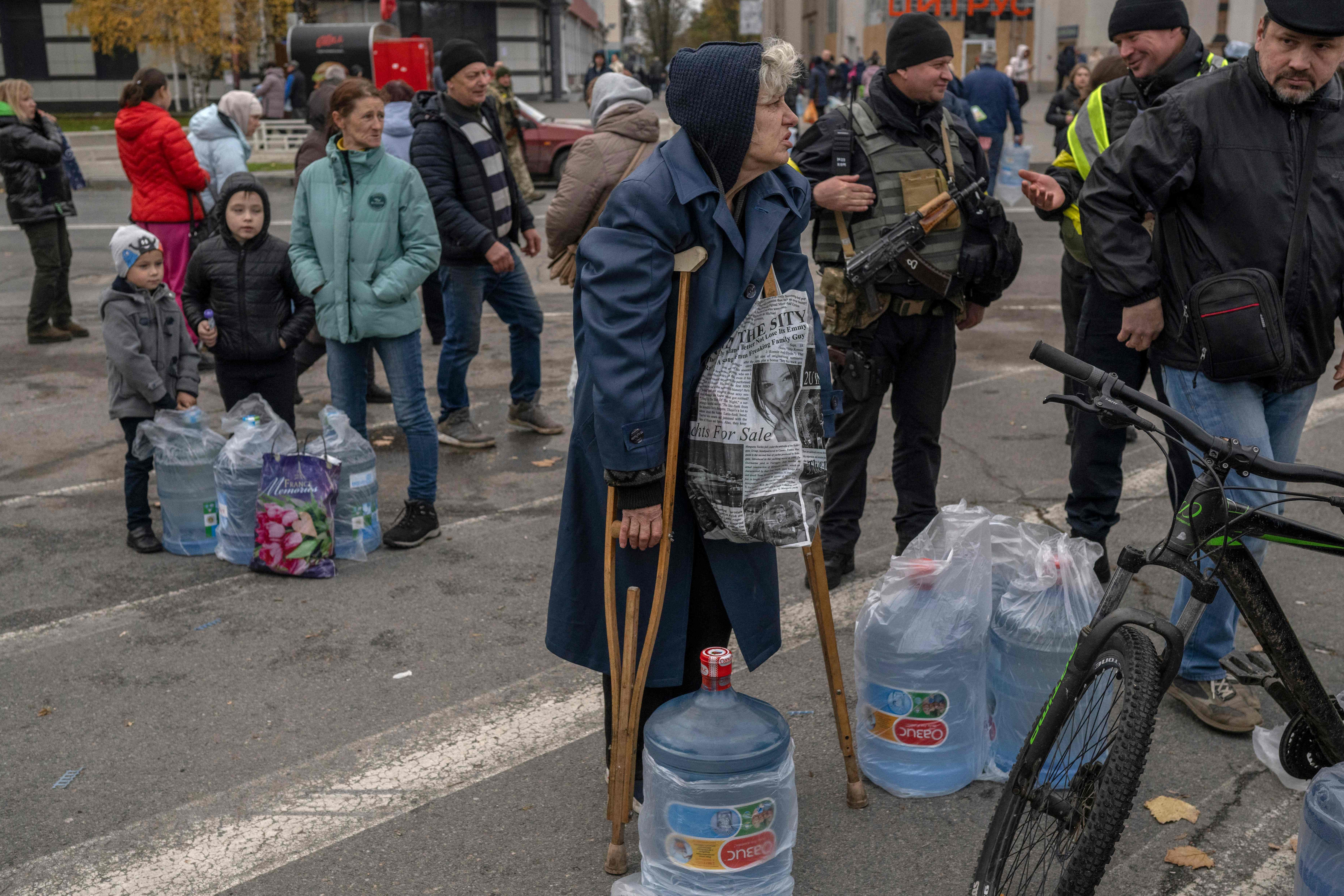 A disabled woman waits for help to carry her water during an aid supply distribution in the centre of Kherson