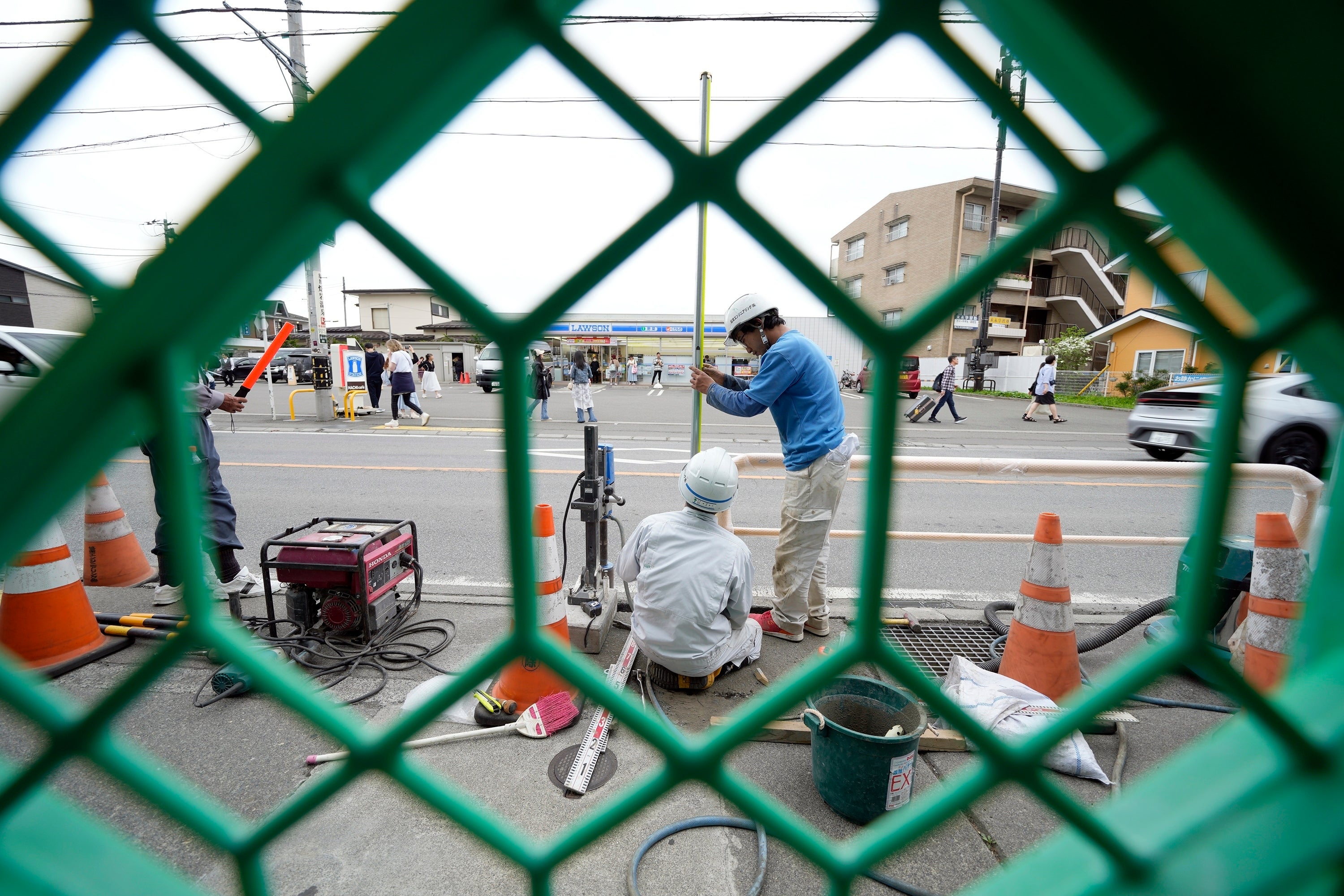 Workers set up a barricade near the Lawson convenience store, background, Tuesday, April 30, 2024, at Fujikawaguchiko