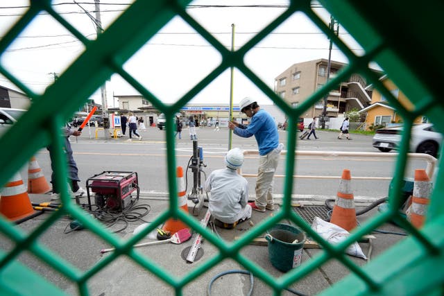 <p>Workers set up a barricade near the Lawson convenience store, background, Tuesday, April 30, 2024, at Fujikawaguchiko </p>