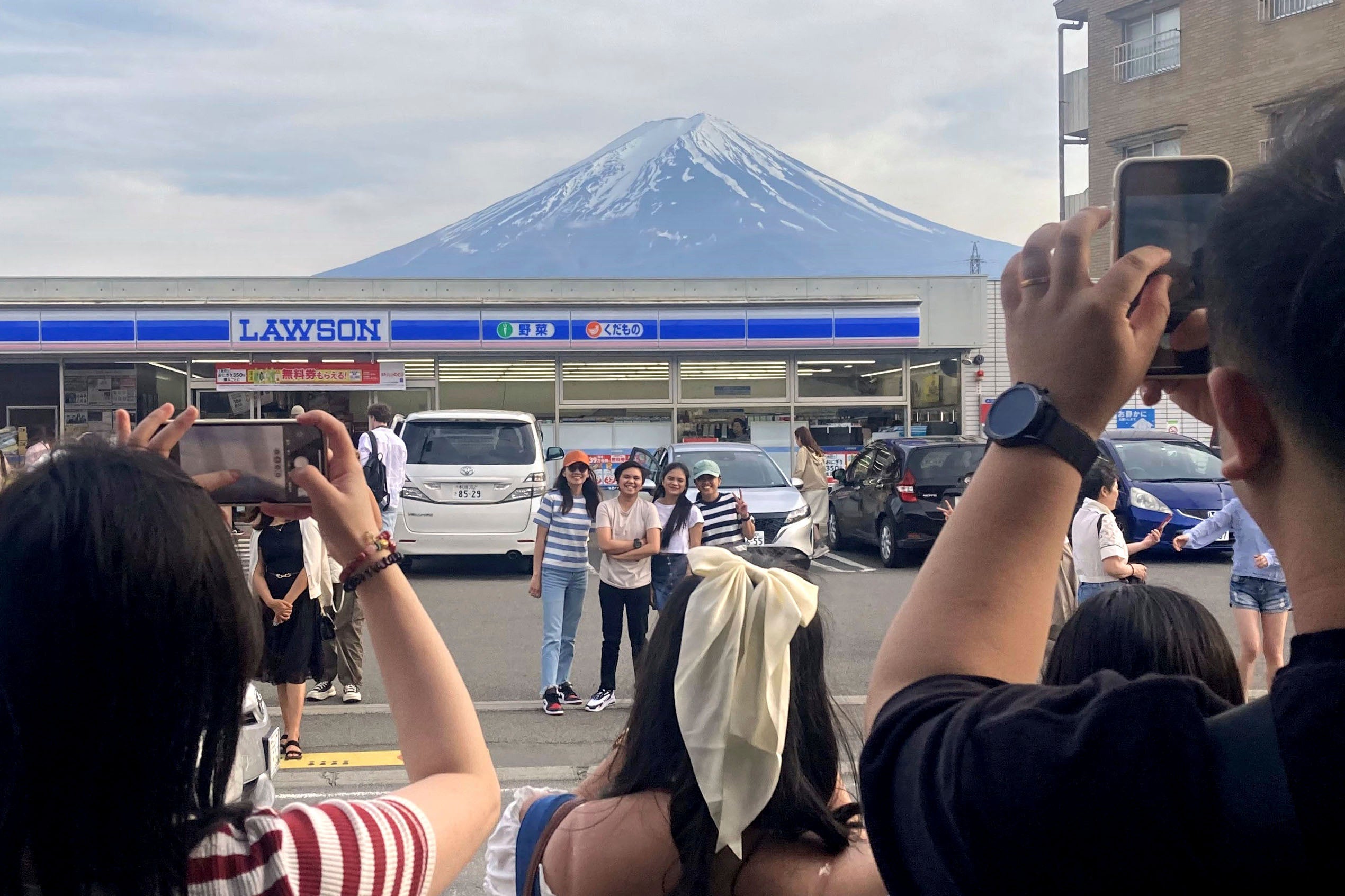 Visitors take a photo in front of a convenient store at Fujikawaguchiko town, Yamanashi prefecture, Japan