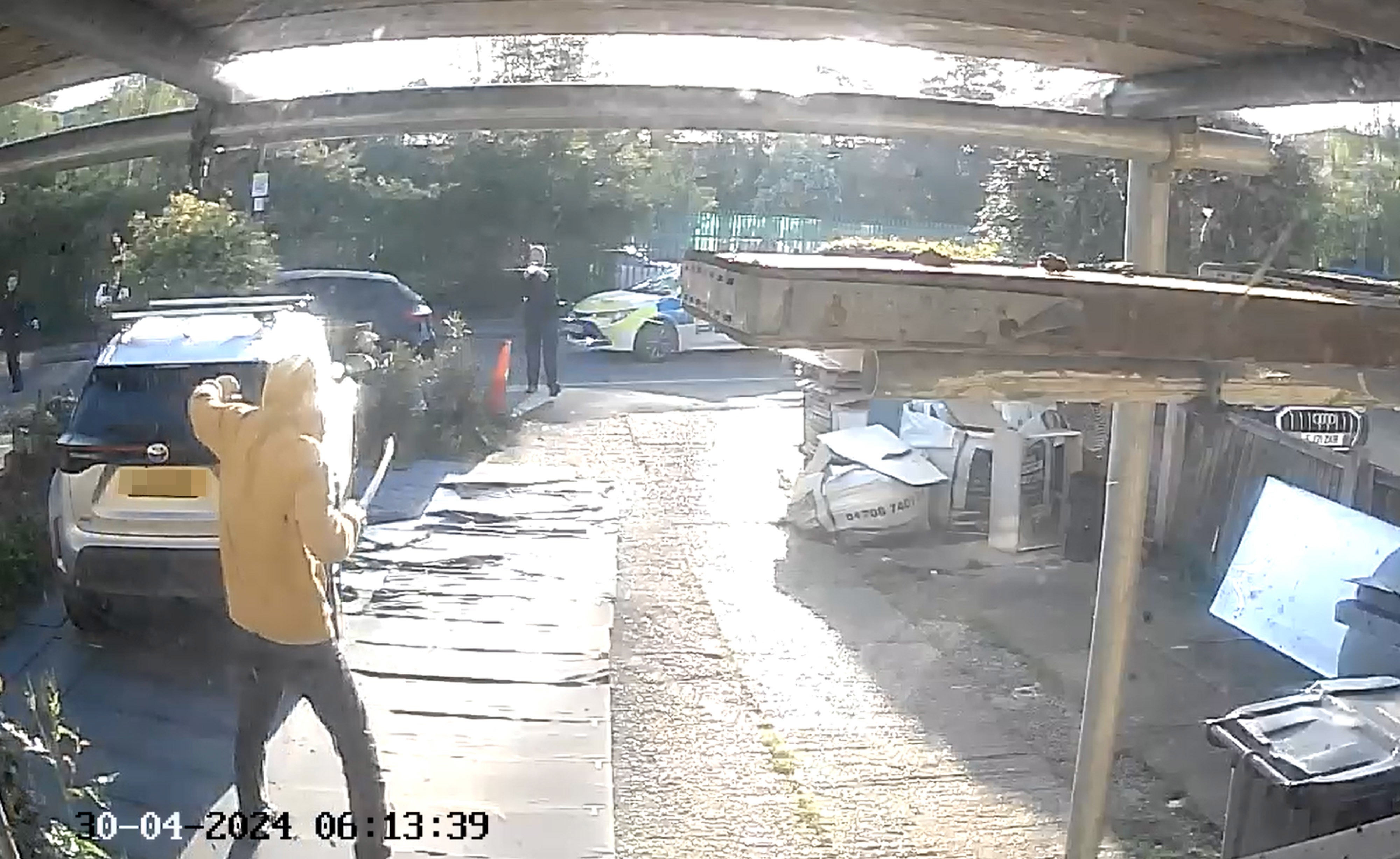 A lone police officer apprehends a man in a yellow hoodie