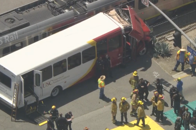 <p>Firefighters stand near a bus from the University of Southern California that collided with a Los Angeles Metro train on 30 April, 2024</p>