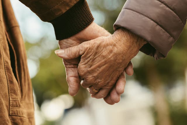 <p>Close up of elderly couple holding hands and walking outdoors</p>