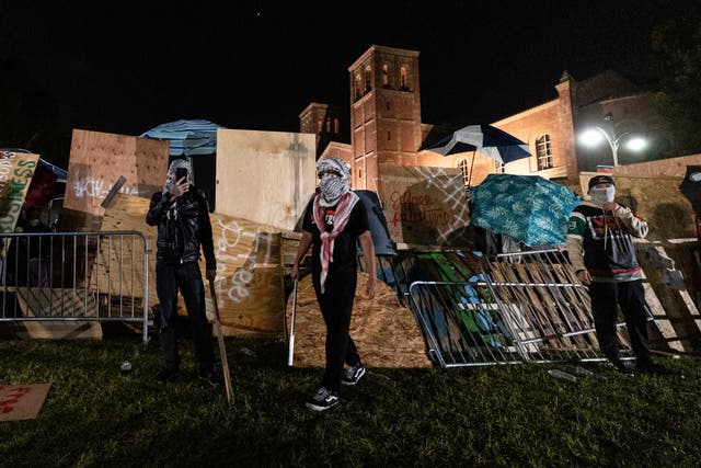 Pro-Palestinian demonstrators regroup and rebuild the barricade surrounding the encampment at UCLA as clashes erupt