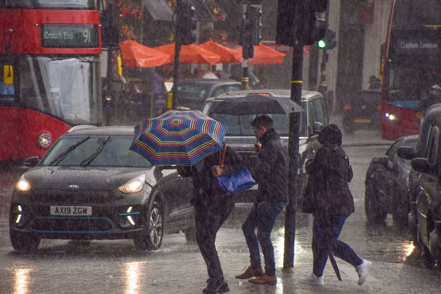 <p>People run for cover in Trafalgar Square, London, as torrential rain falls</p>