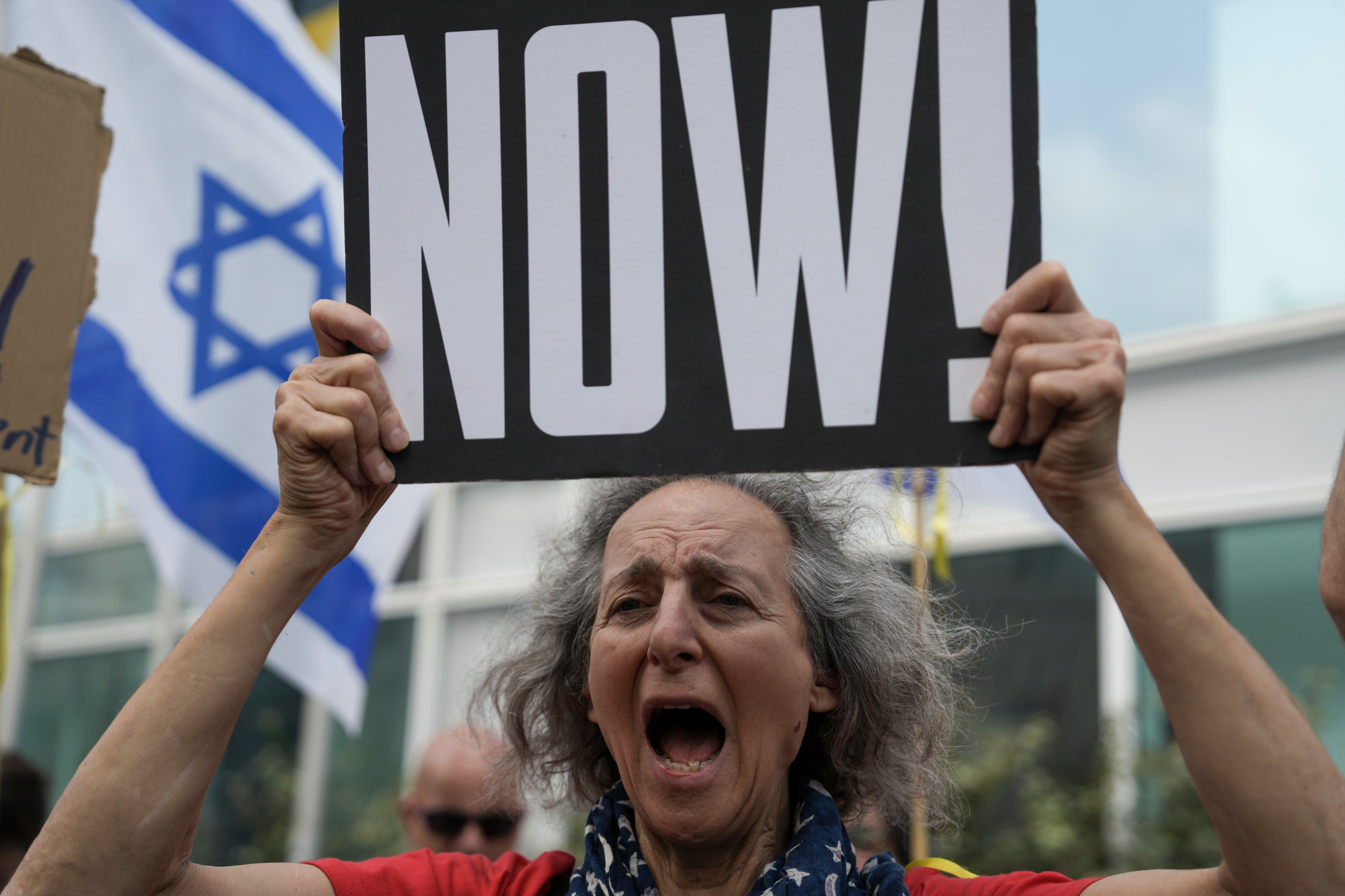 A woman holds a banner and shouts slogans with families and supporters of Israeli hostages held by Hamas in Gaza during a protest calling for their return