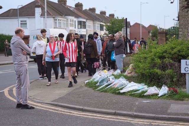 Members of the community looking at floral tributes in Hainault, north east London (Yui Mok/PA)