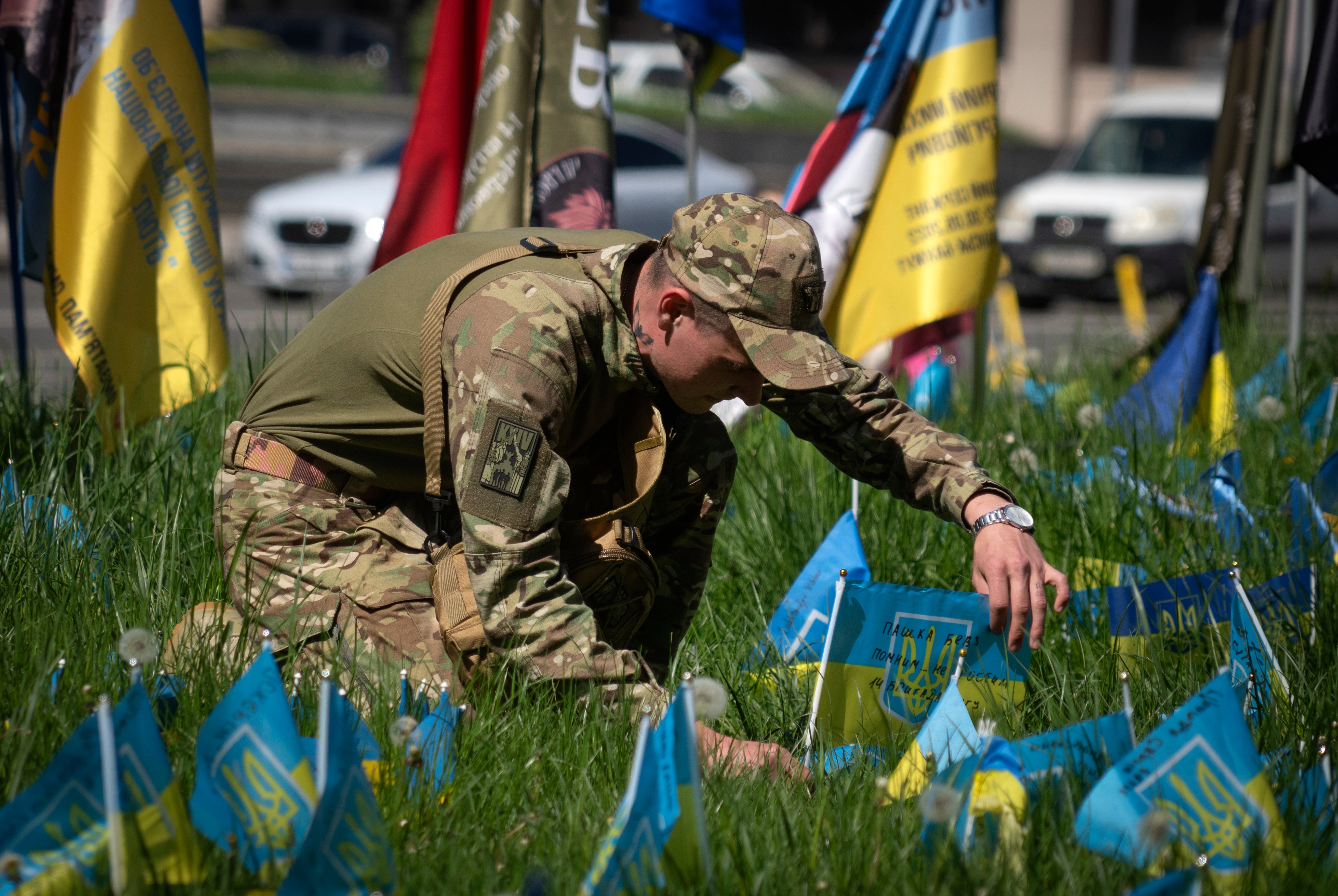 A Ukrainian soldier instals a national flag on a grassed area at the Independence square in Kyiv