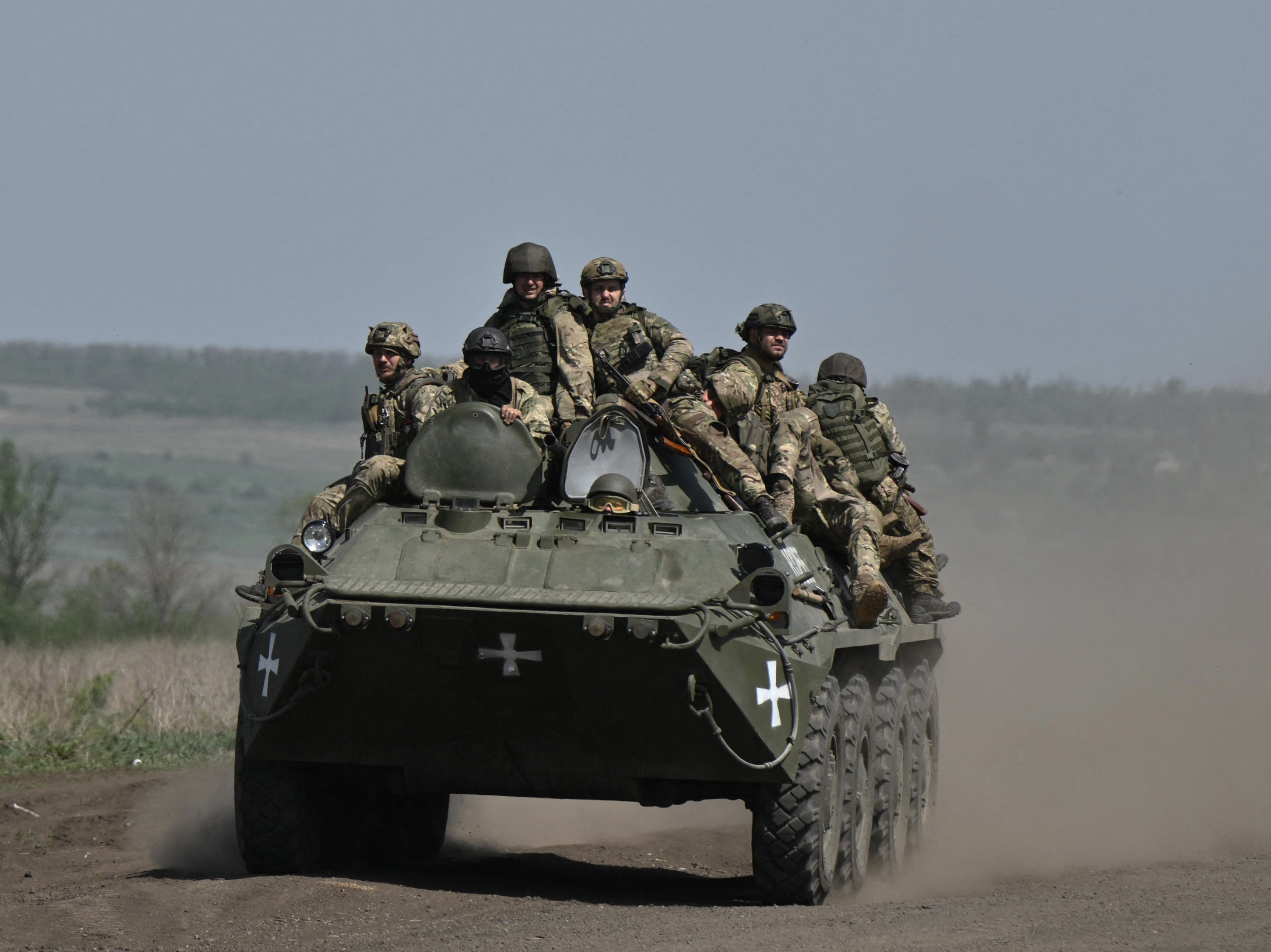 Ukrainian servicemen ride on an armored personnel carrier (APC) in a field near Chasiv Yar, Donetsk region