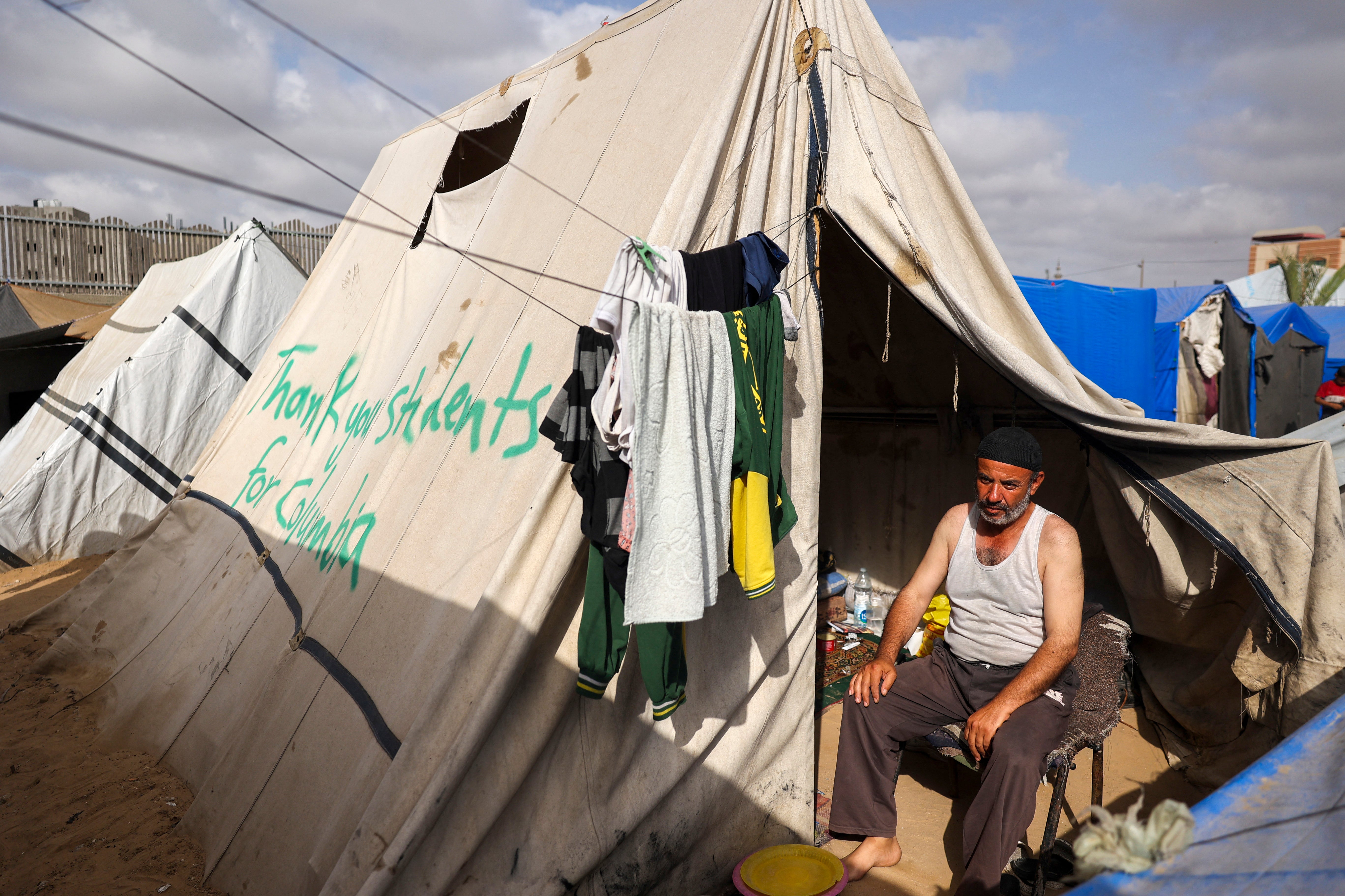 A man sits in Rafah in a tent with the message “thank you students for Columbia” painted on the side on 27 April. The New York Police Department has arrested hundreds of protesters at Columbia since their protests began on 17 April
