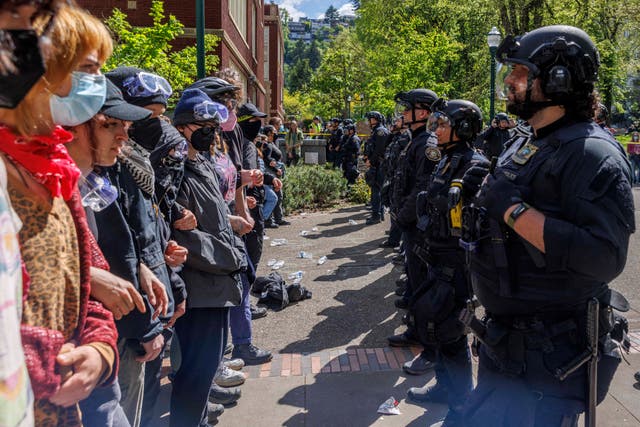 <p>Pro-Palestinian students and activists face police officers after protesters were evicted from the library on campus earlier in the day at Portland State University in Portland, Oregon on May 2, 2024</p>