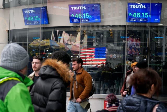 <p> Pedestrians walk past the Nasdaq building as the stock price of Trump Media & Technology Group Corp. is displayed on screens, 26 March 2024, in New York</p>