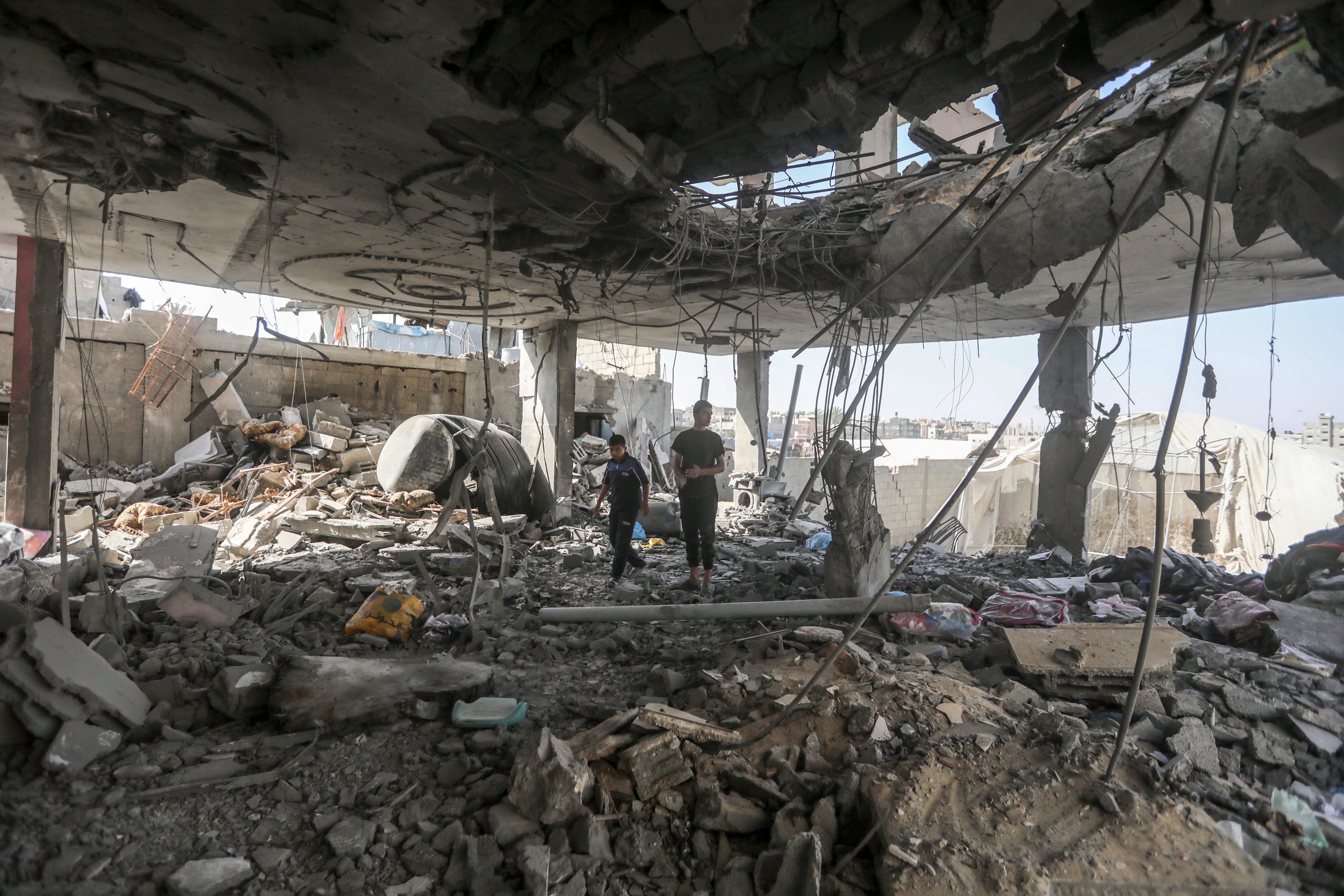 Palestinians stand in the ruins of a family home after an overnight Israeli attack