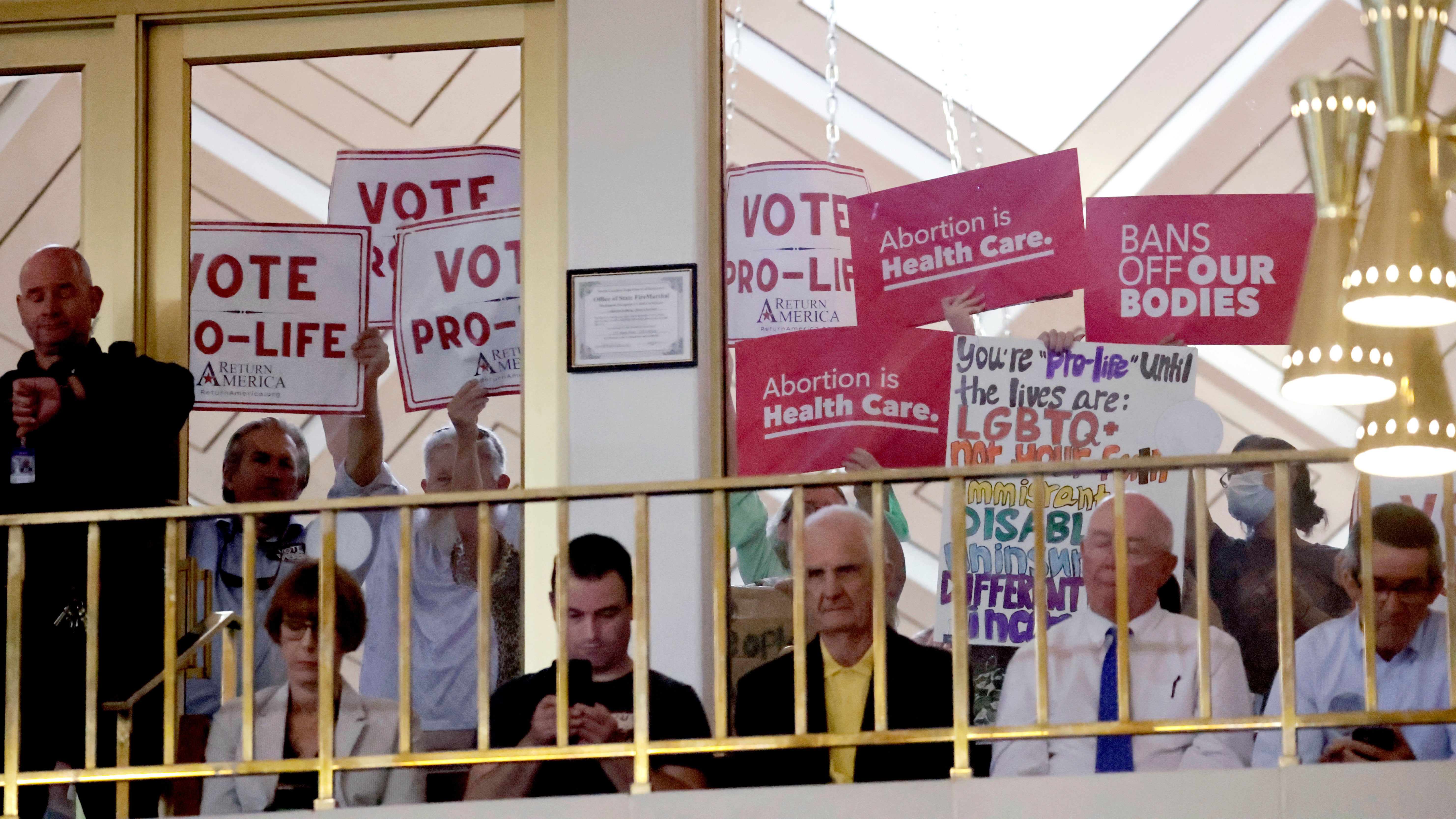 Protesters on both sides of the issue hold signs as North Carolina House members debate abortion access on May 16, 2023