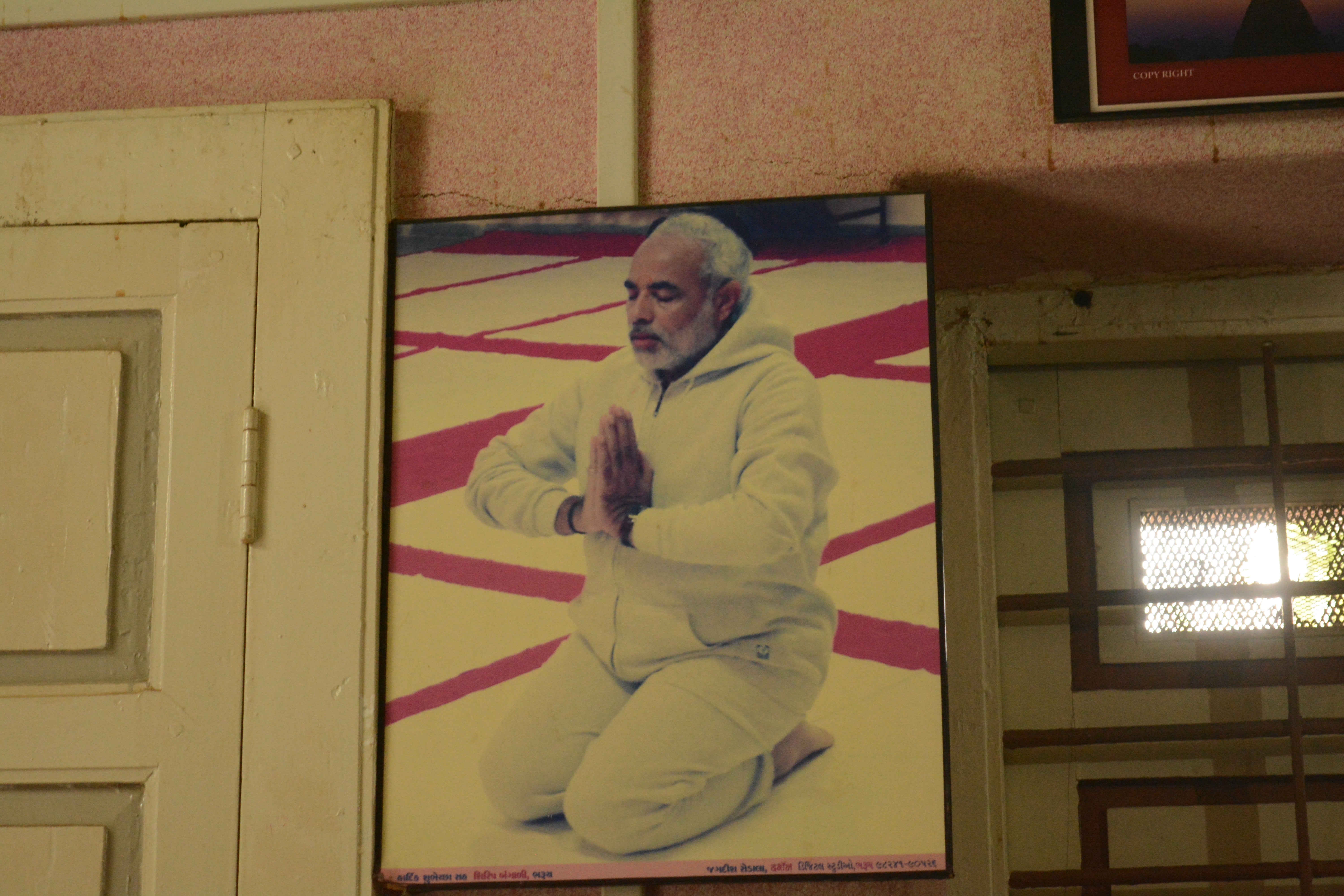 A framed picture of Narendra Modi on the wall of his brother Somabhai’s dimly lit and sparsely furnished office in Vadnagar
