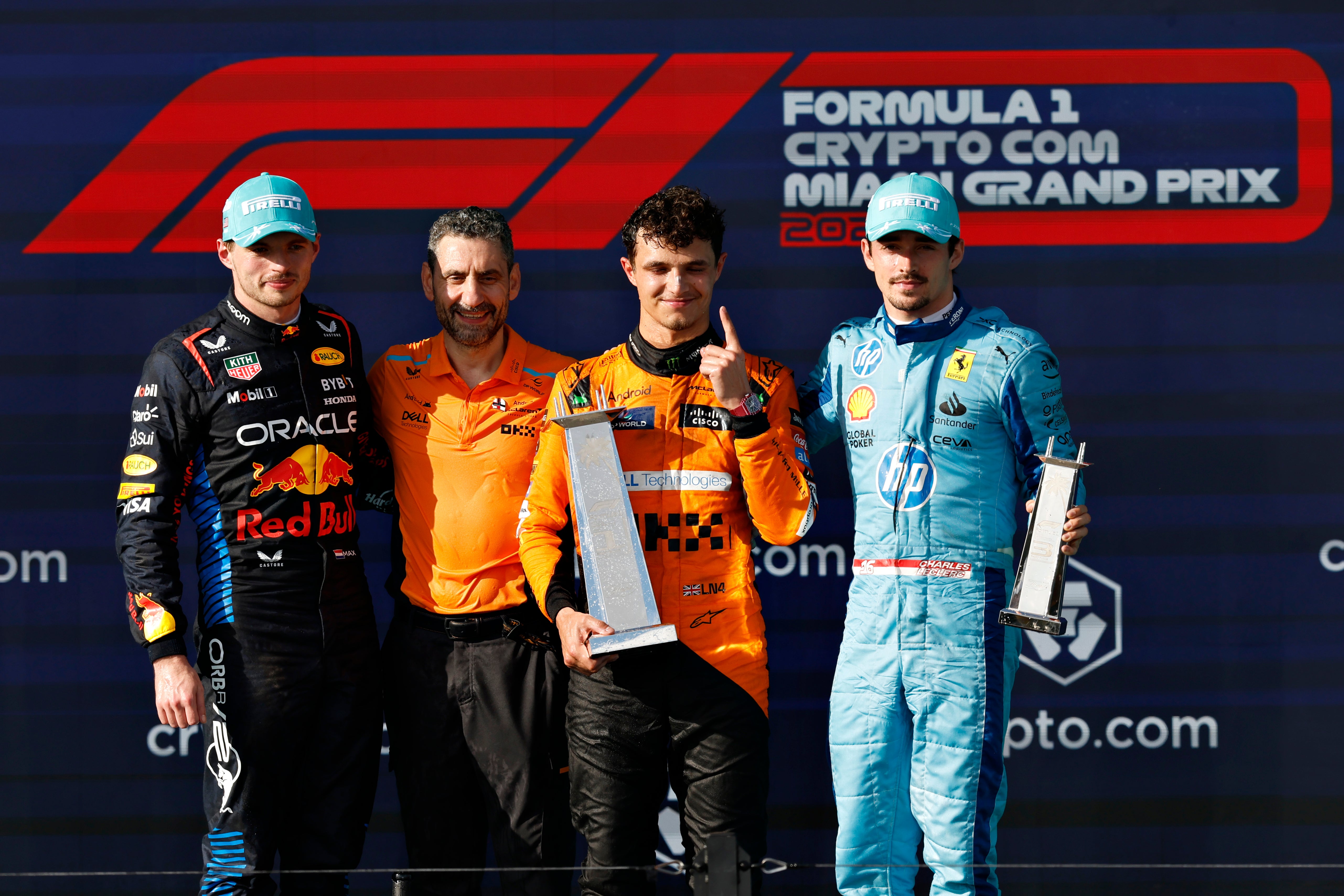 Norris smiles on top of the podium alongside McLaren team principal Andrea Stella (centre-left), Max Verstappen (left) and Charles Leclerc (right)