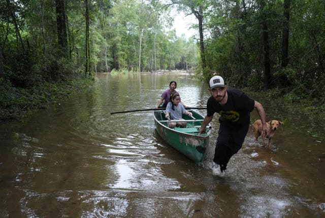 <p>Alvaro Trevino pulls a canoe with Jennifer Tellez and Ailyn, 8, after they checked on their home on Sunday, May 5, 2024, in Spendora, Texas</p>