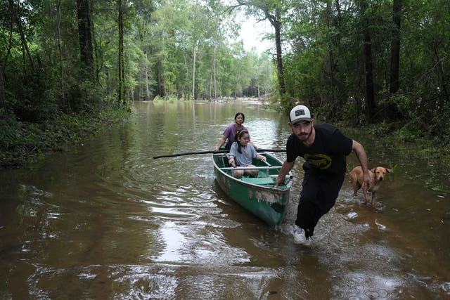 <p>Alvaro Trevino pulls a canoe with Jennifer Tellez and Ailyn, 8, after they checked on their home on Sunday, May 5, 2024, in Spendora, Texas</p>