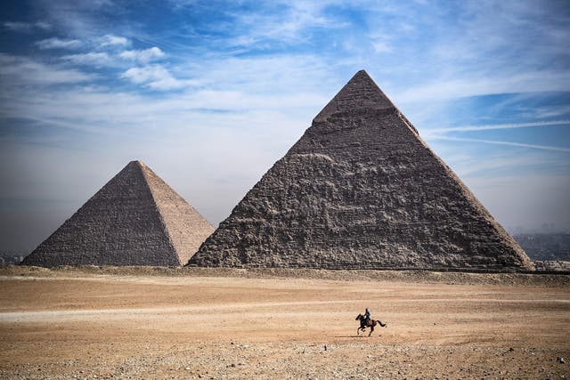 <p>A man rides a horse in front of the Giza pyramids necropolis on the outskirts of Cairo, Egypt, on 26 January, 2021</p>
