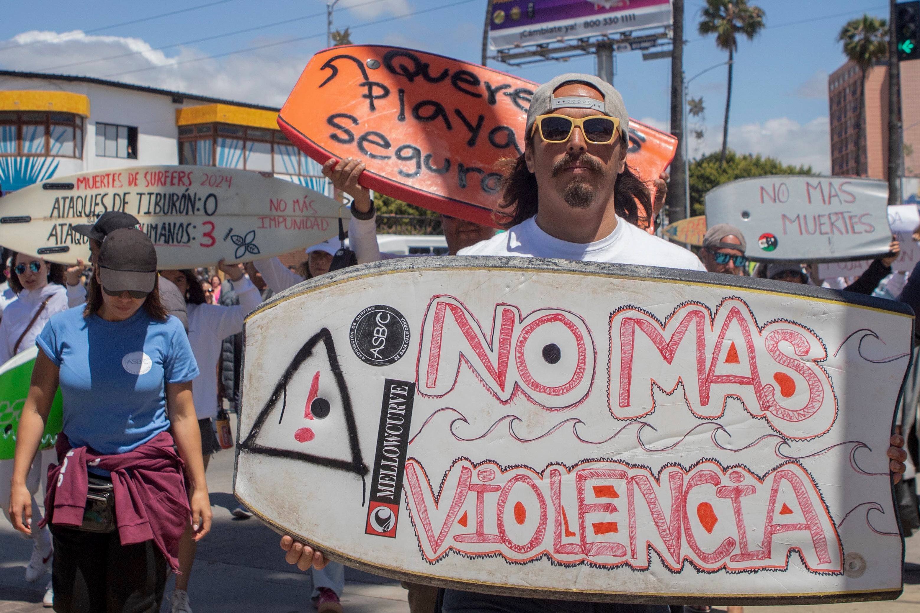 A demonstrator holding a bodyboard written in Spanish ‘No more violence’
