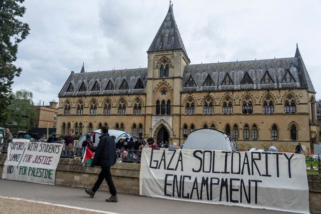 <p>People walk past a pro-Palestine encampment set up by students at Oxford University</p>