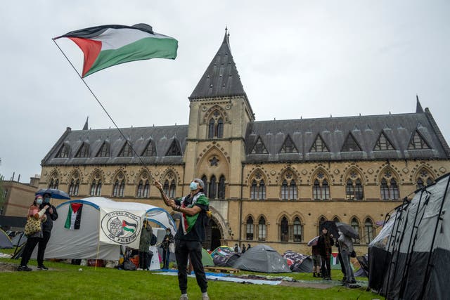 <p>A student activist waves a Palestinian flag at an encampment at Oxford University</p>