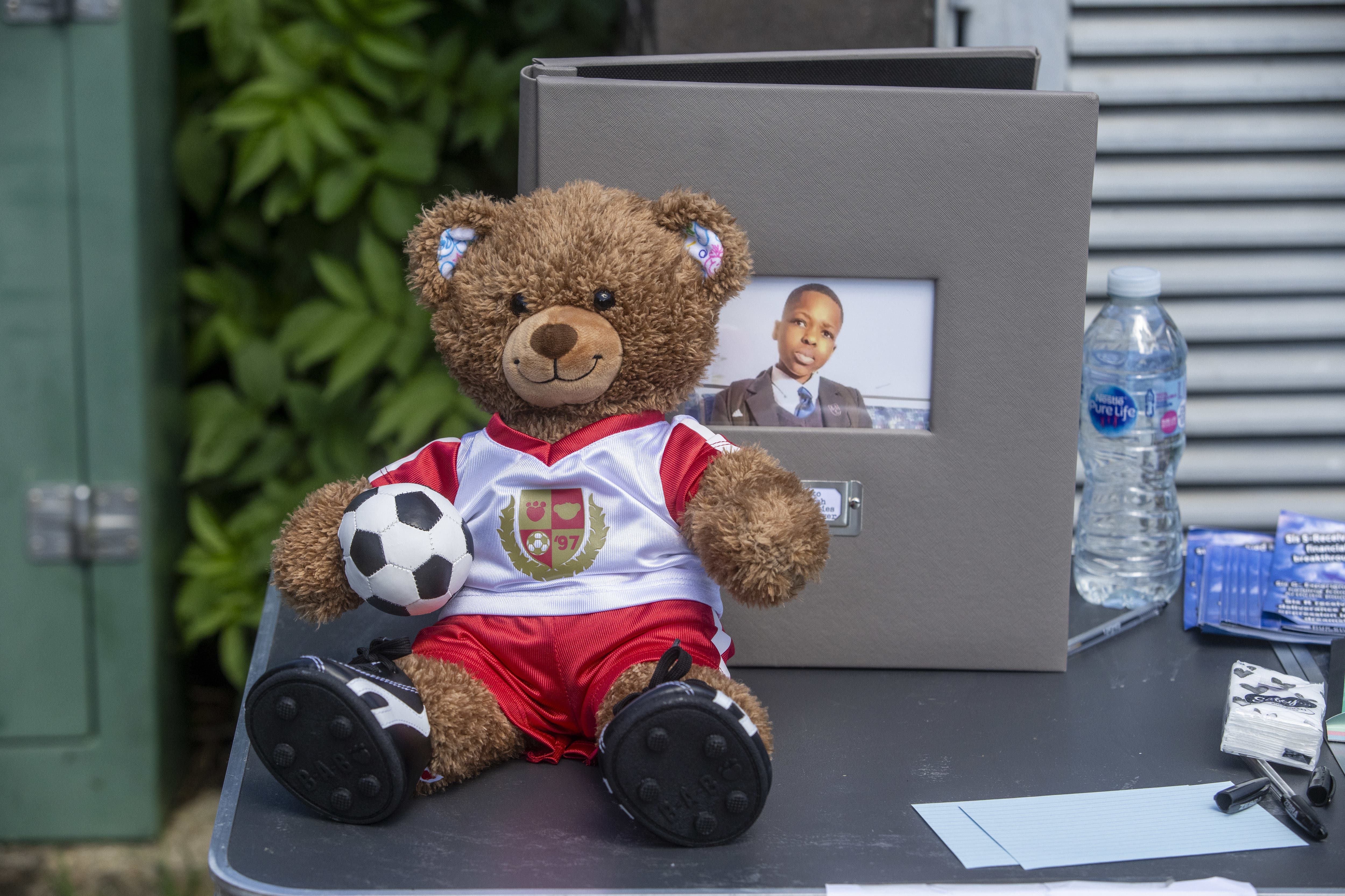 A teddy bear in an Arsenal top on a table at vigil at Hainault Underground Station Car Park, north east London, in memory of 14-year-old Daniel Anjorin, who was killed in a sword attack (Jeff Moore/PA)