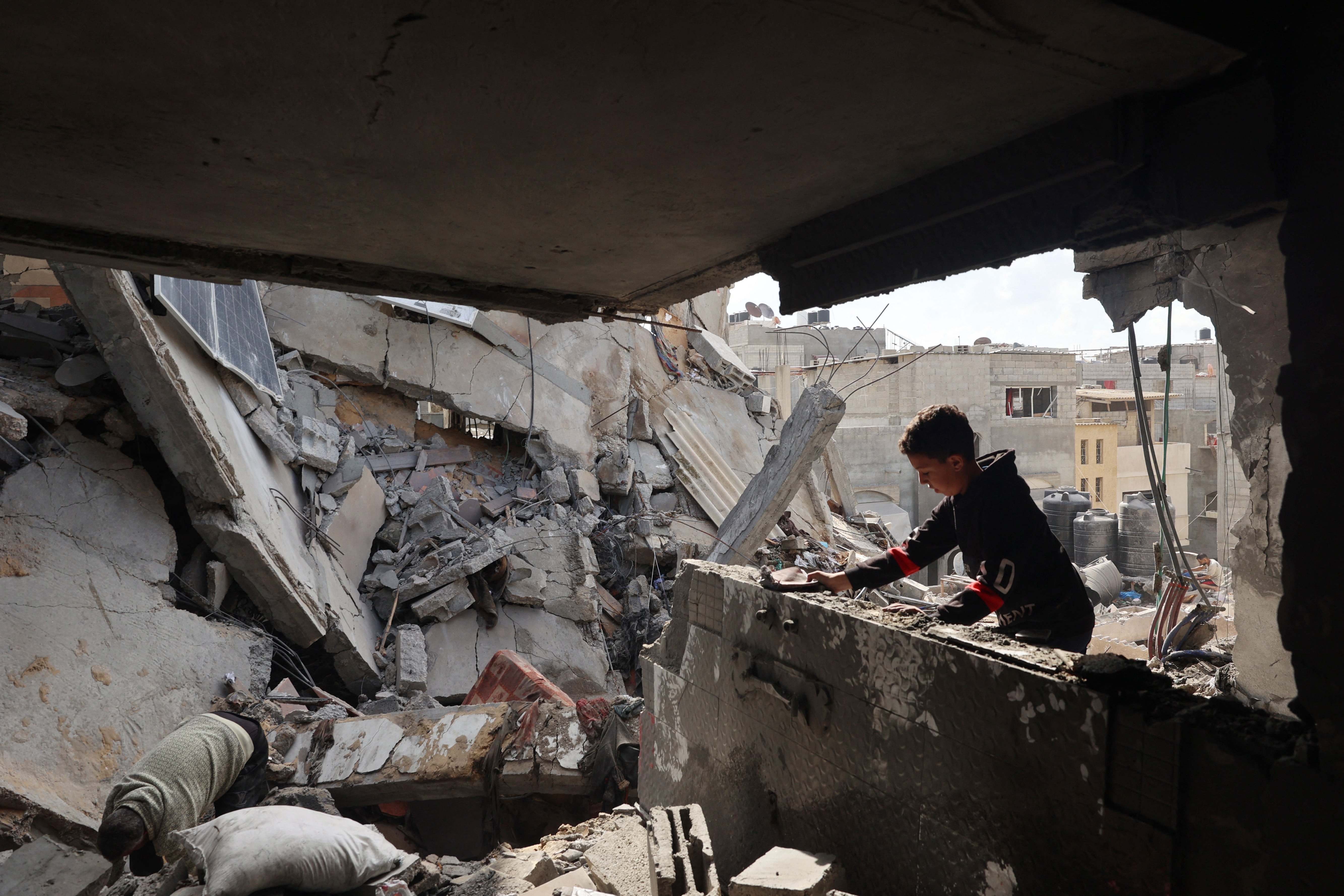 Palestinians inspect the damage following Israeli bombardment of Rafah's Tal al-Sultan district in the southern Gaza Strip