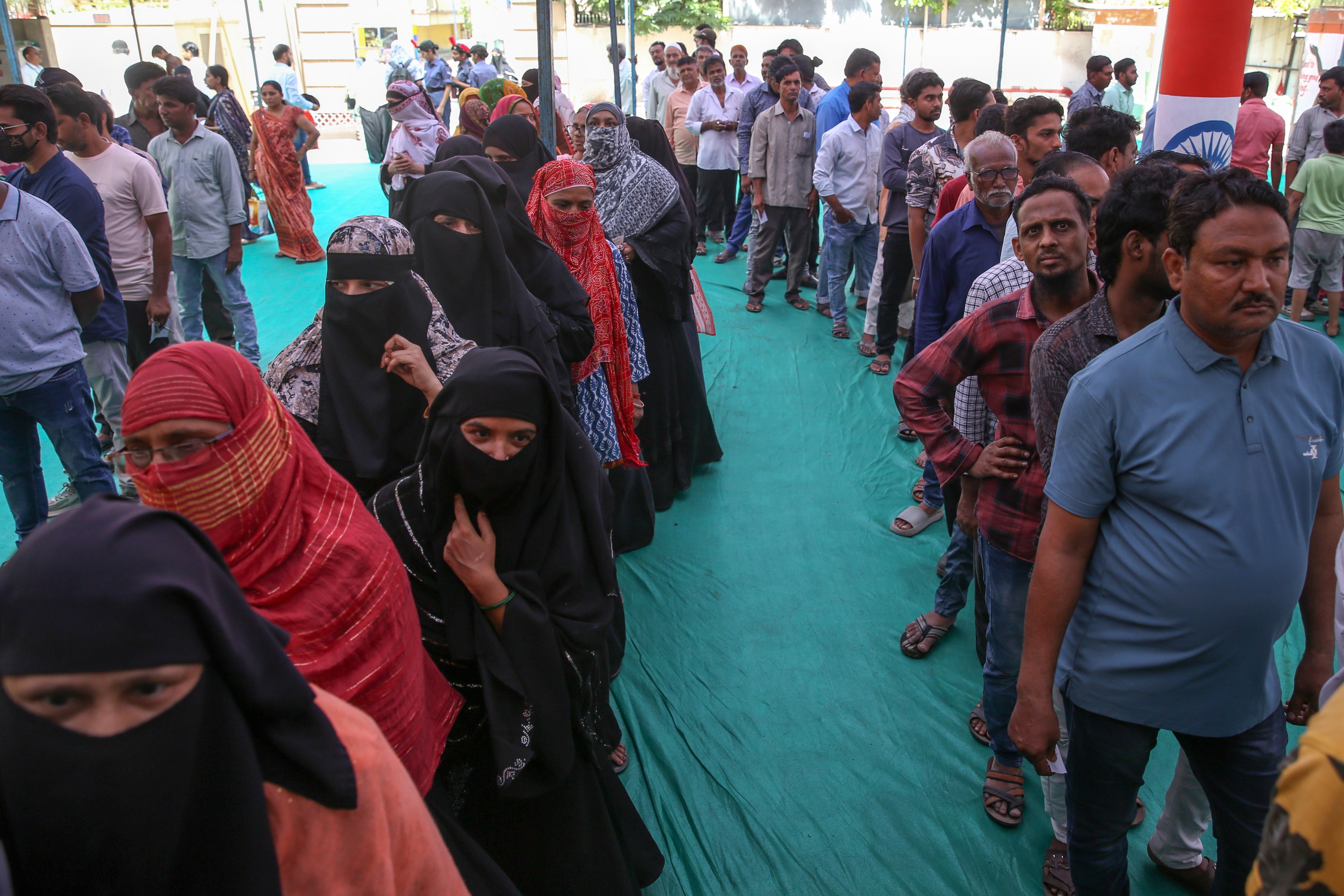 Indian voters wait outside a polling station during the third phase of the election in Ahmedabad, Gujarat