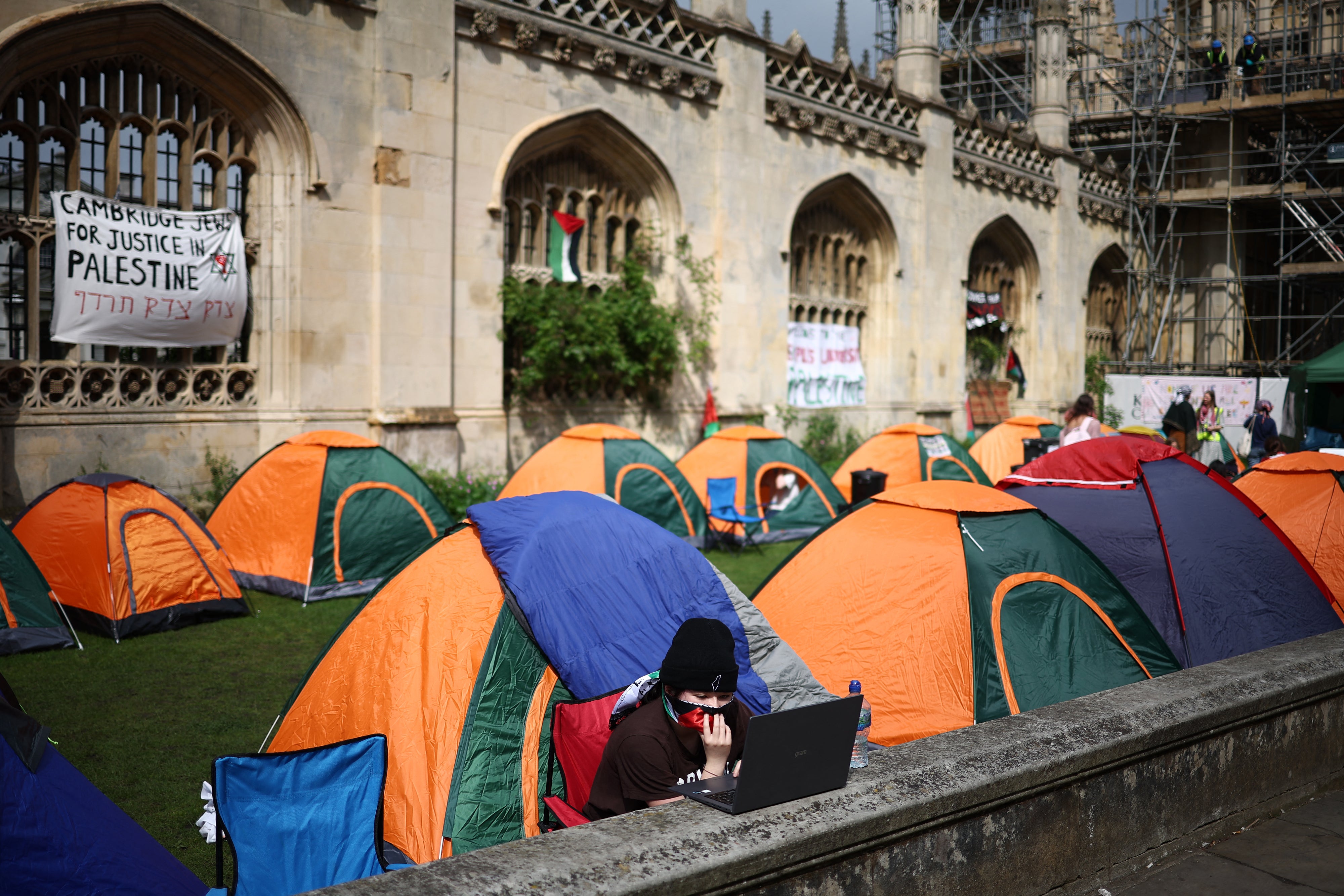 A person works on a laptop computer as they sit by tents during a protest in support of Palestinian people, at King’s College at Cambridge